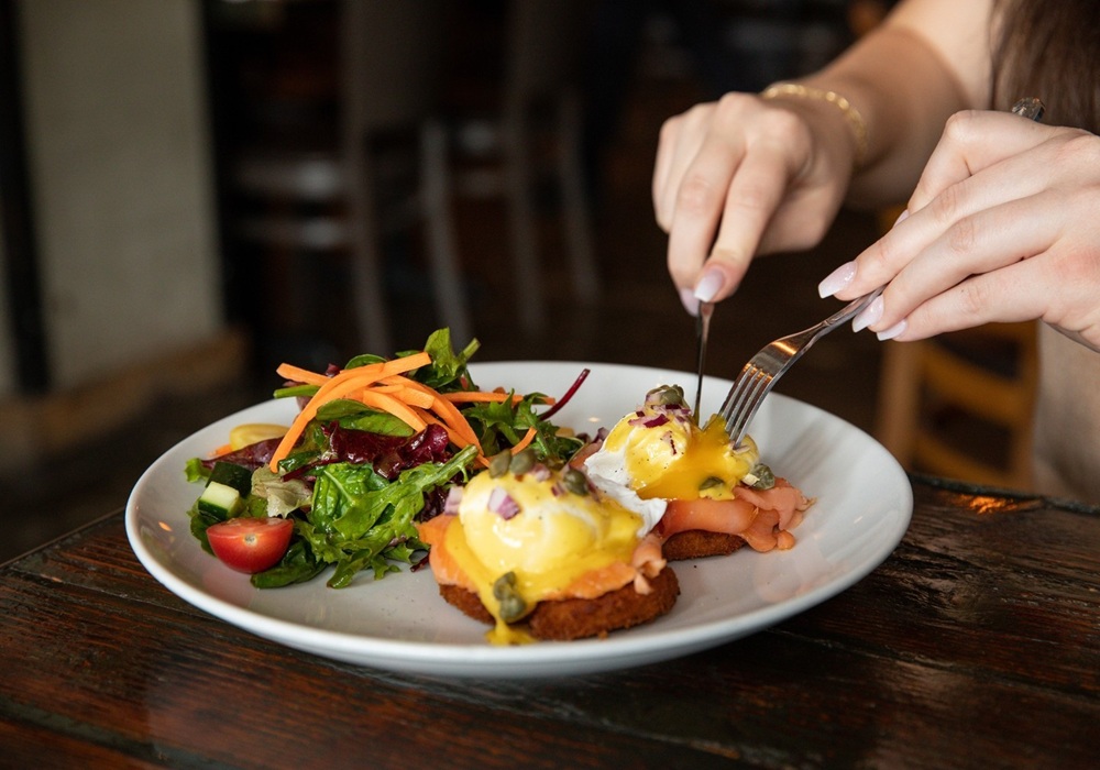 two eggs benedict with a side of vegetable salad