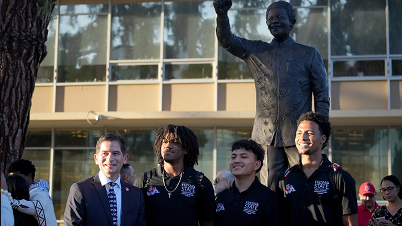 Fresno State President Saúl Jiménez-Sandoval and Fresno State students at the Nelson Mandela monument at the campus Peace Garden