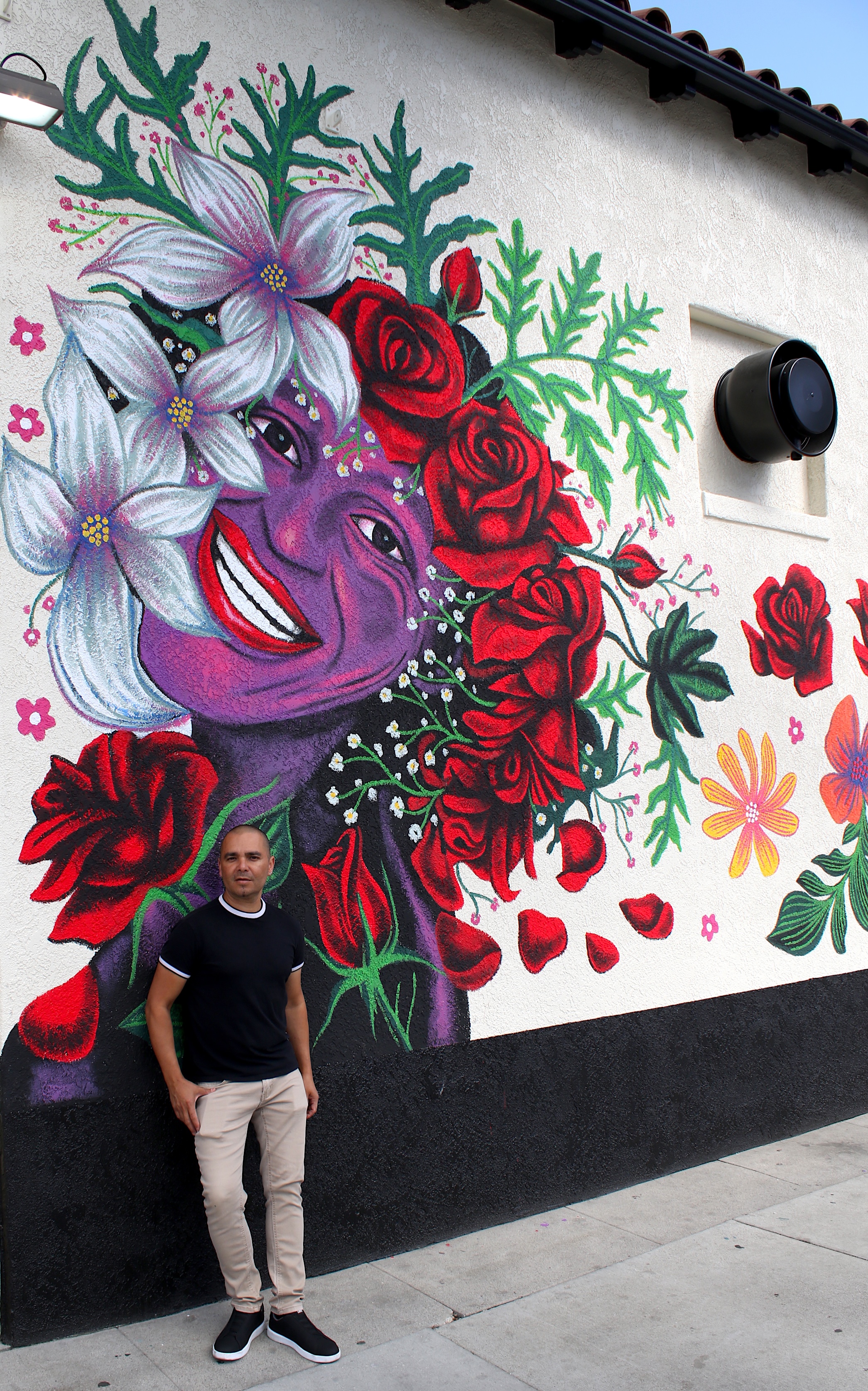 Artist Eddie Jelinet poses with his latest mural, honoring LGBTQ+...