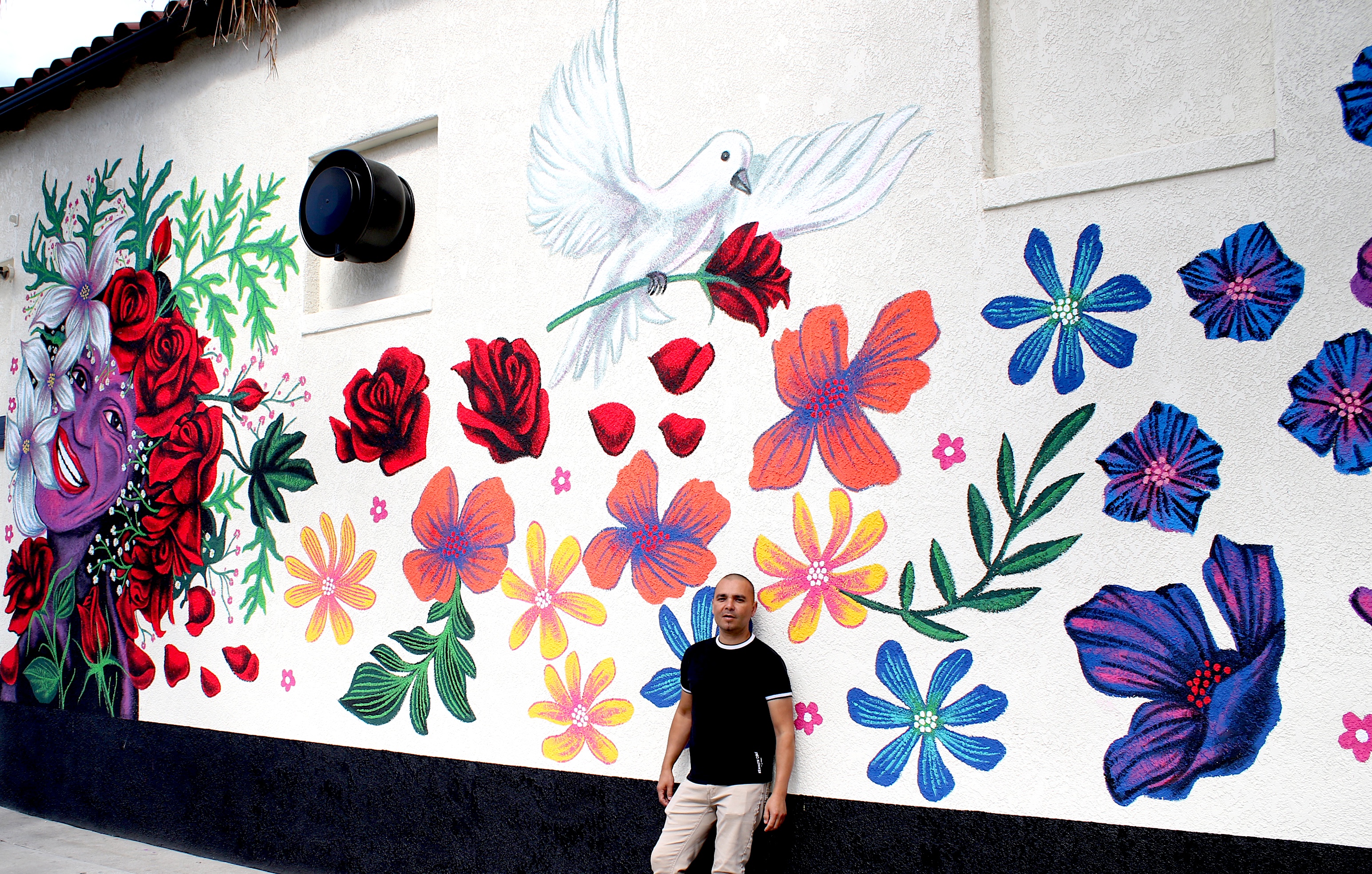 Artist Eddie Jelinet poses with his latest mural, honoring LGBTQ+...