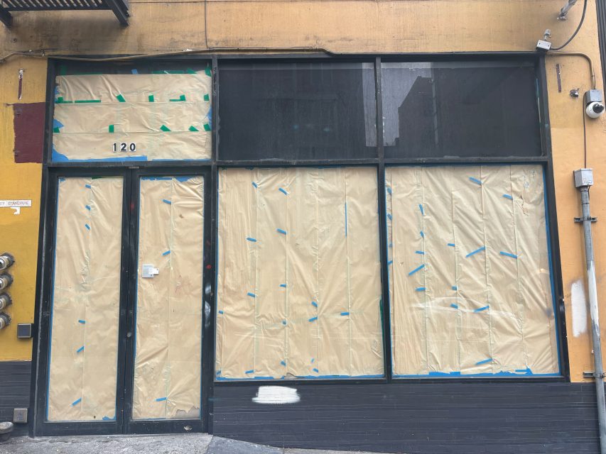 Storefront at 120 with windows and door covered in brown paper and taped, indicating construction or renovation work.
