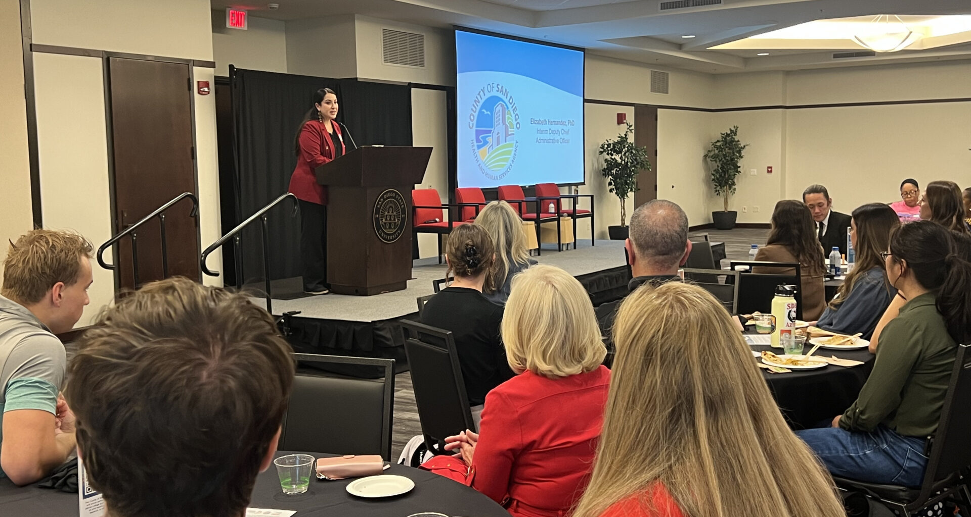 Students in a meeting room listening to speaker behind a podium