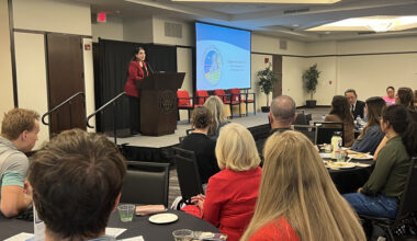 Students in a meeting room listening to speaker behind a podium