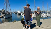 Susan Johnson (right) talks to a father and daughter from Chula Vista about the schooner's temporary reprieve. The "Bill of Rights" (far left) remains docked in the South Bay, Chula Vista, Calif., April 4, 2026.