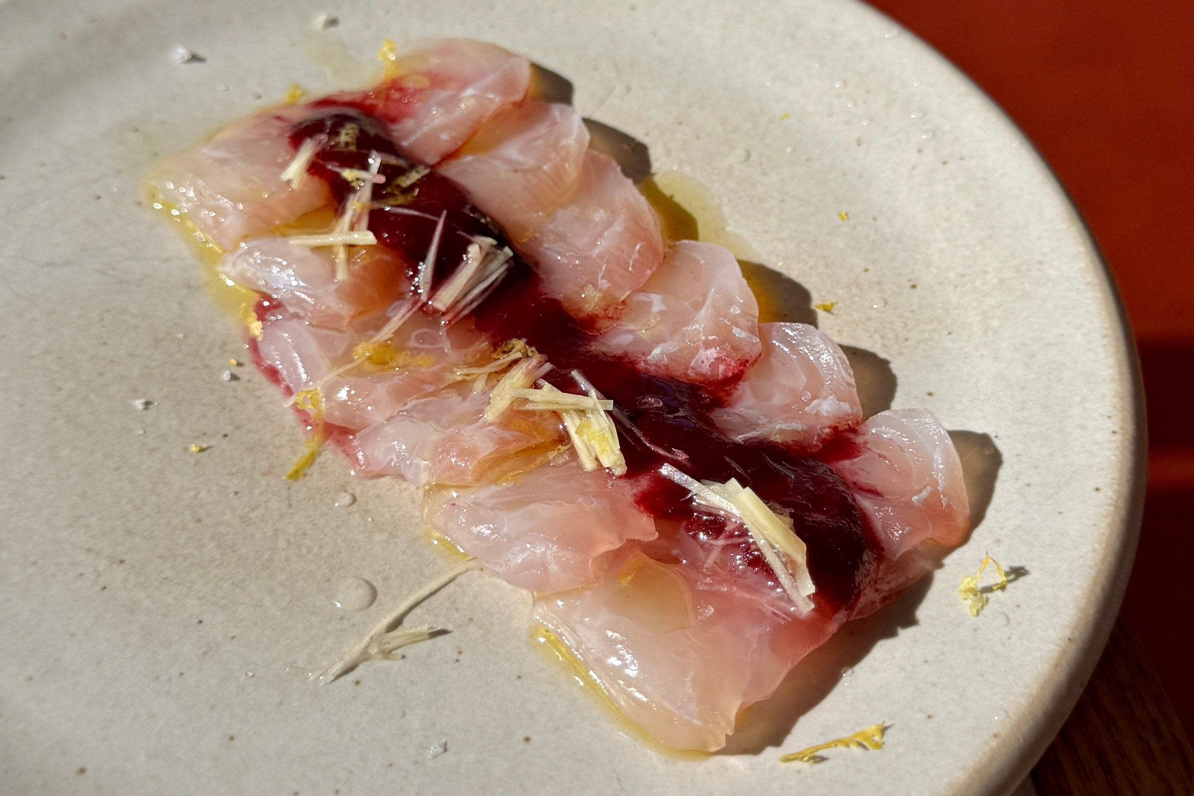 Sliced crudo on a cream-colored plate at Little Fish Melrose Hill.