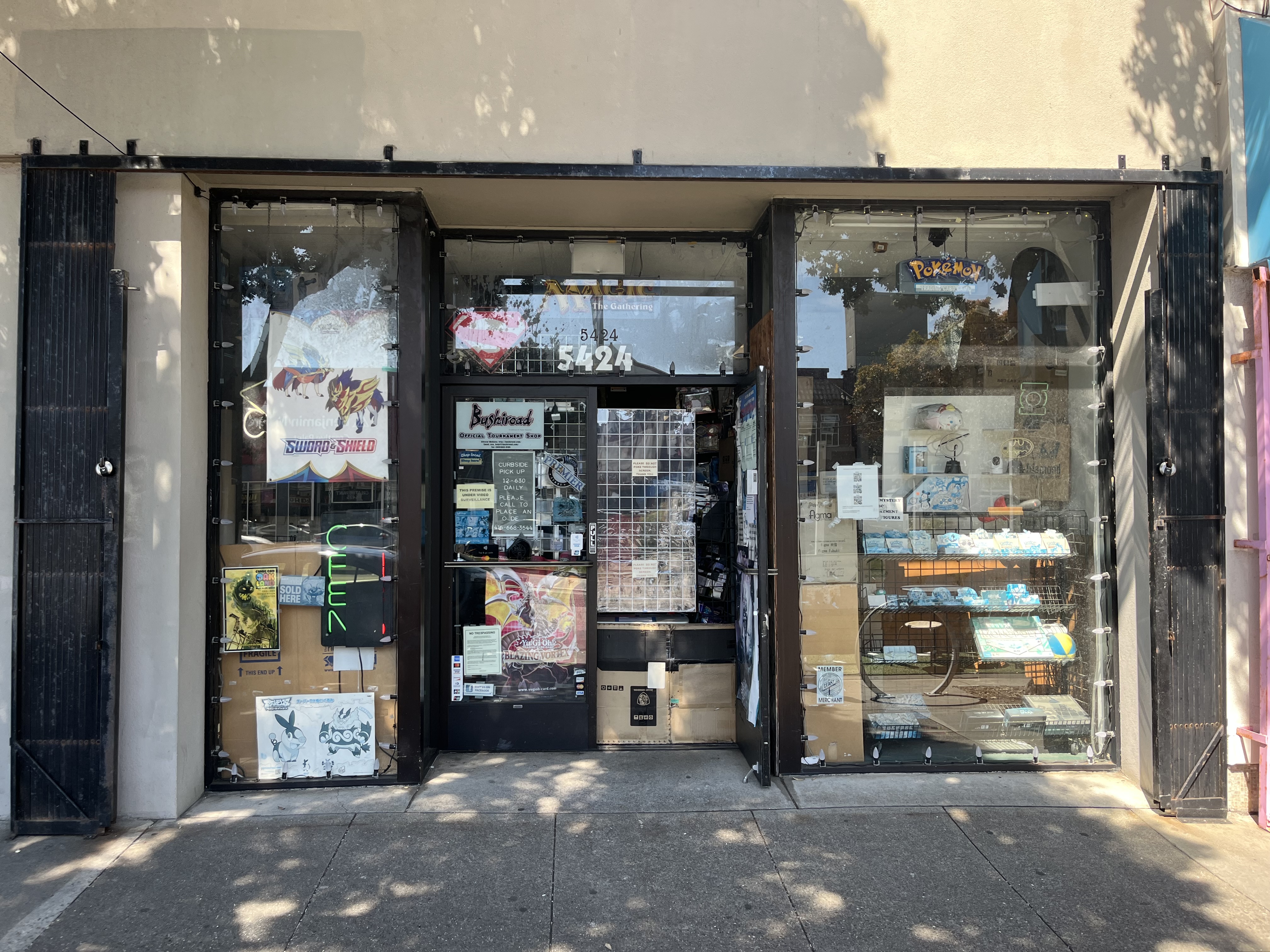 Storefront with a glass door and windows displaying books, posters, and various items; address number 5424 is visible above the entrance.