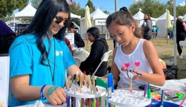 Image from the 2025 NAMIWalks. Woman and small girl sit and paint at a booth