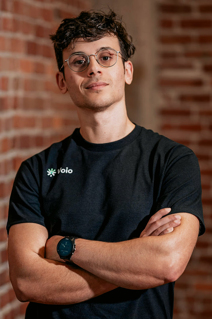Voio co-founder Adam Yala stands near a brick wall