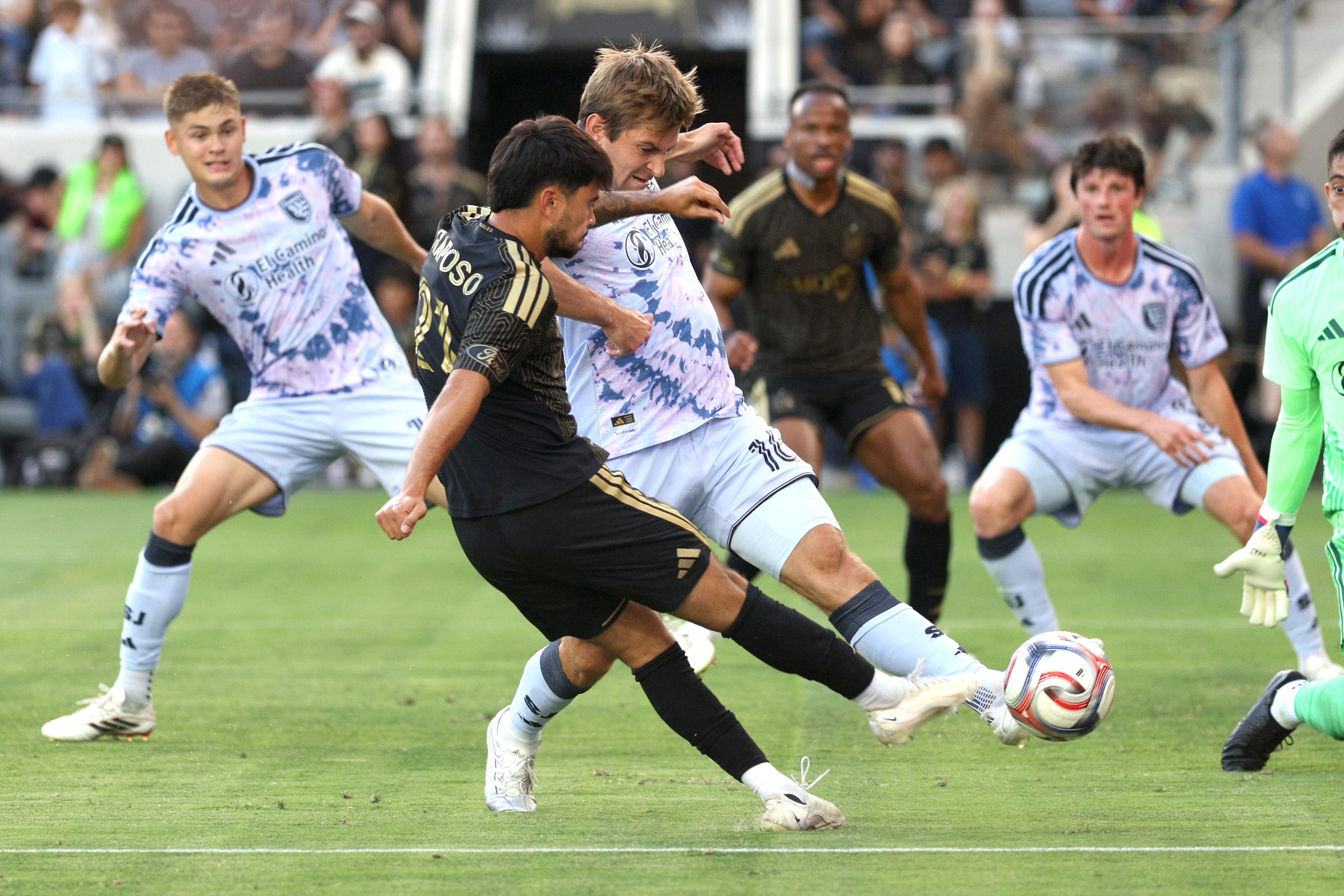 LAFC midfielder Ryan Raposo, front, kicks the ball defended by...