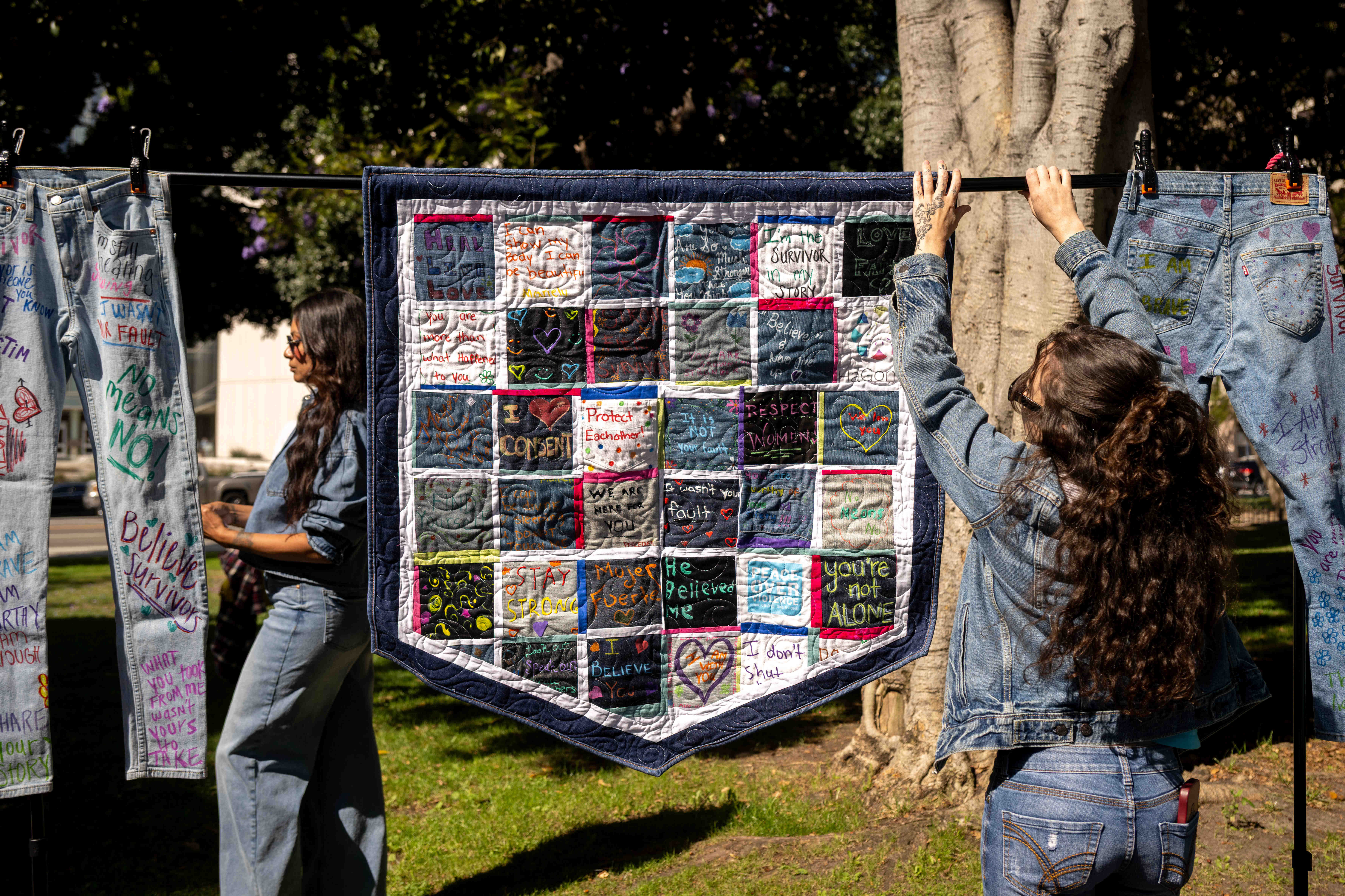 Gabee Benson, a volunteer at HaGomel, hangs their quilt and...