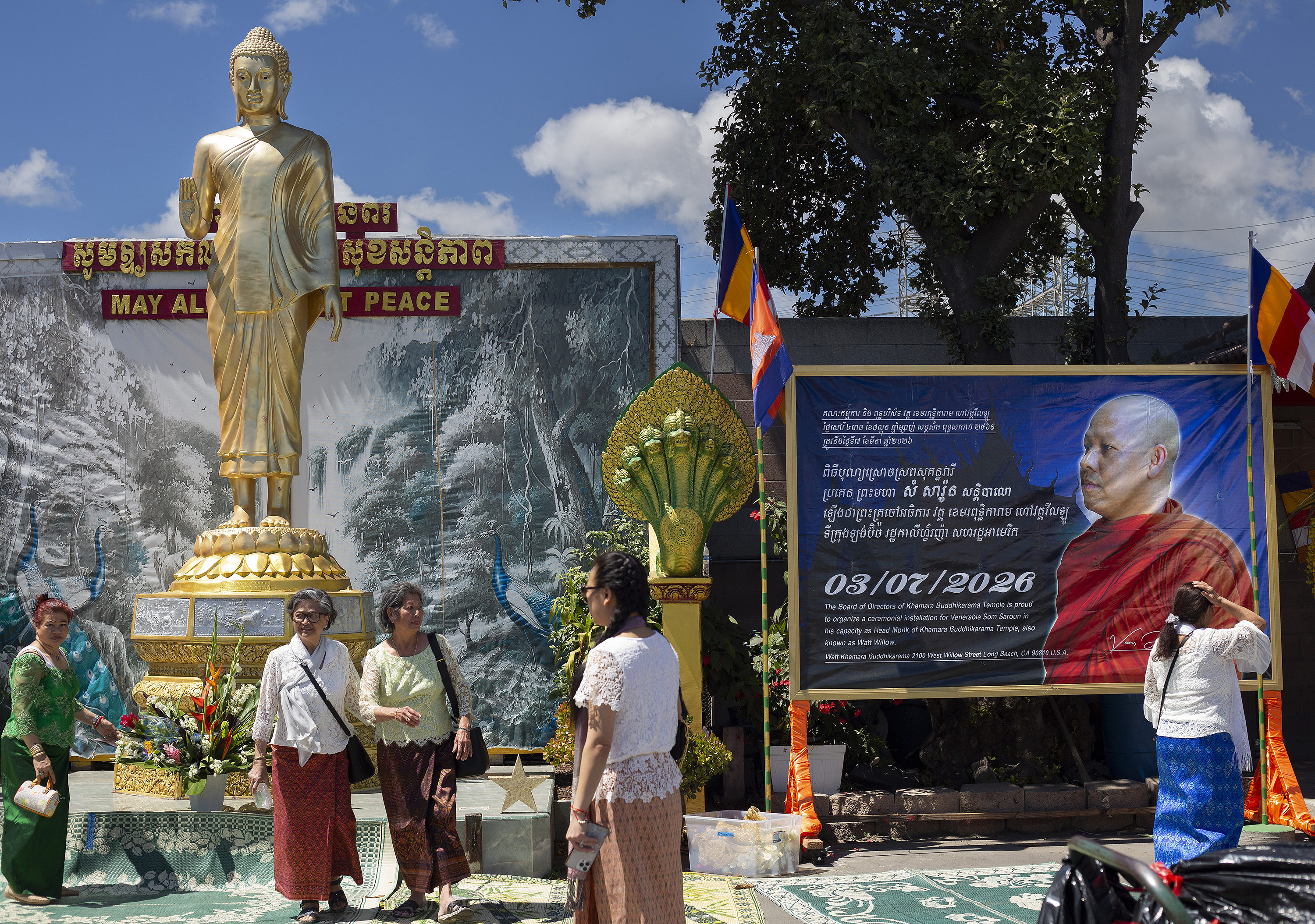 Visitors check the temple grounds which includes a statue of...