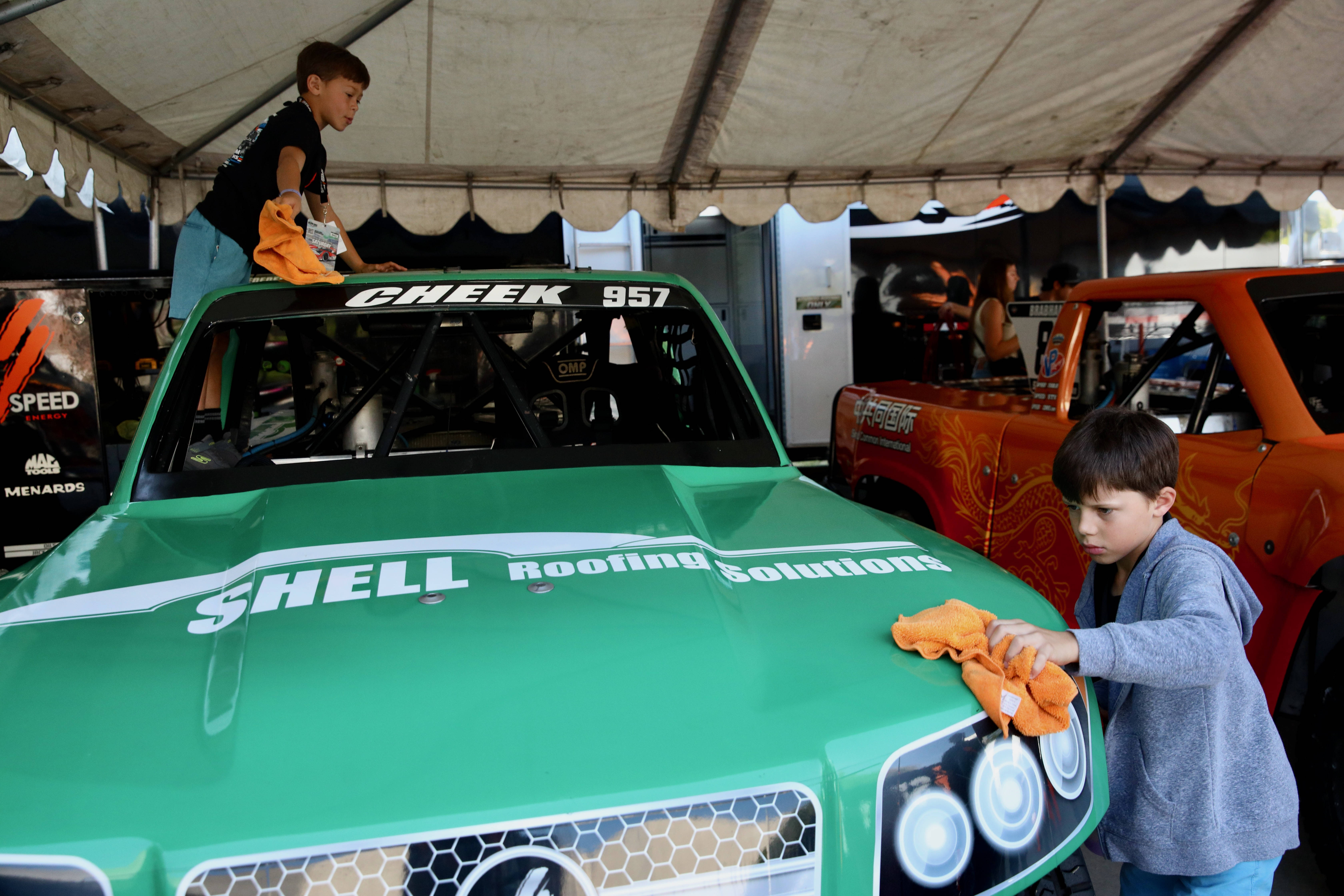 Young crew members spiff up a Stadium Super Truck in...