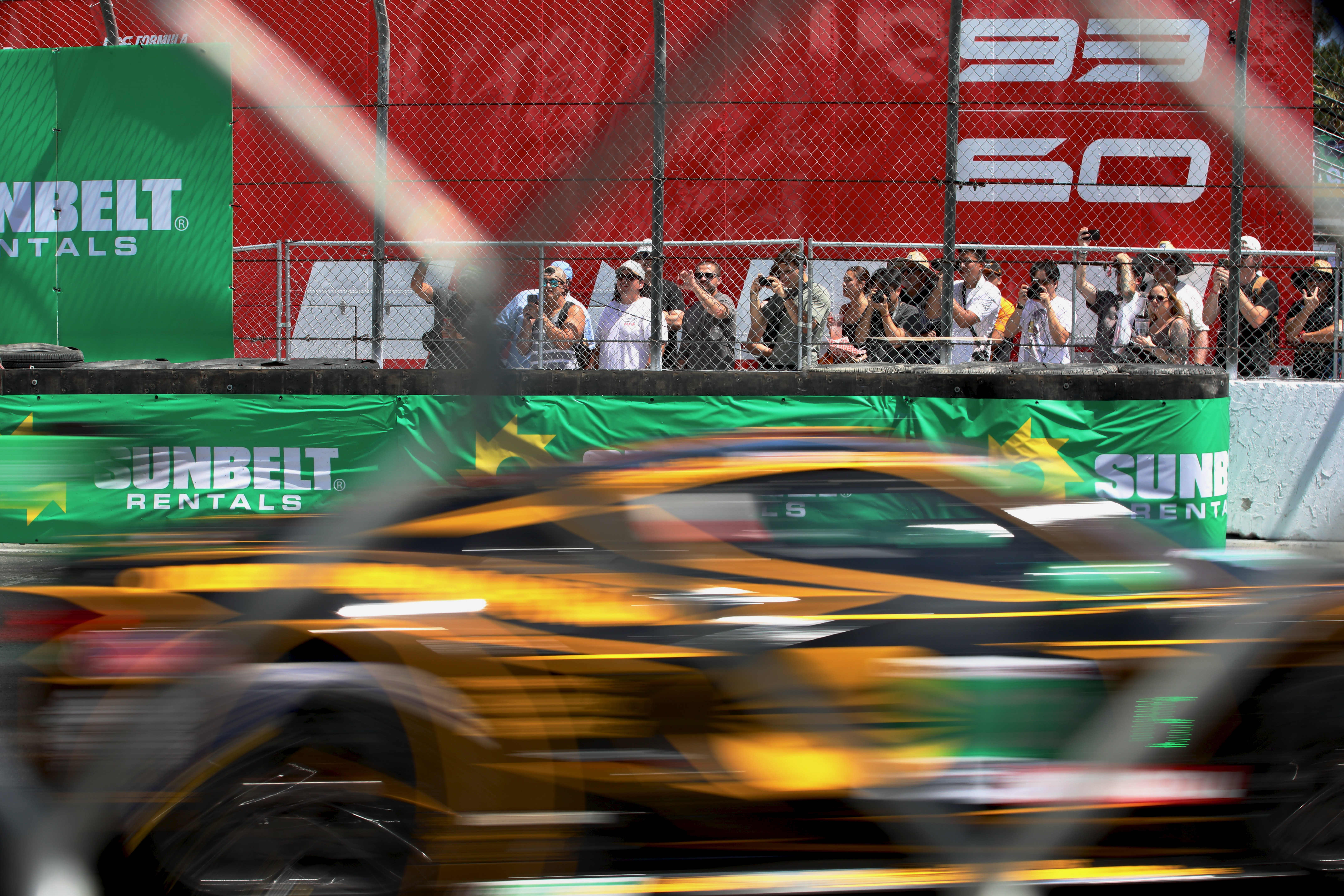 Spectators peer through the fence for the IMSA WeatherTech SportsCar...