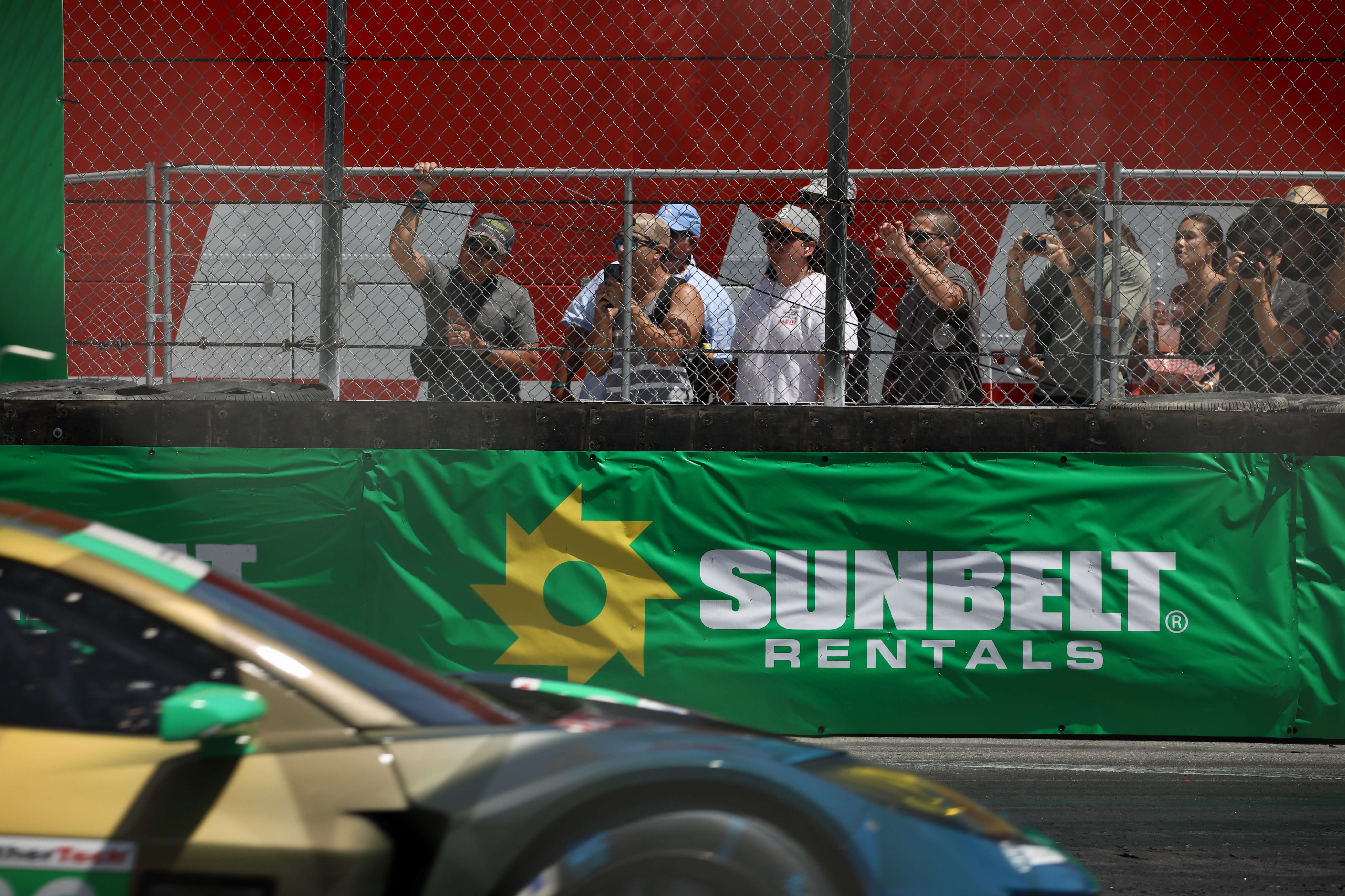 Spectators peer through the fence for the IMSA WeatherTech SportsCar...