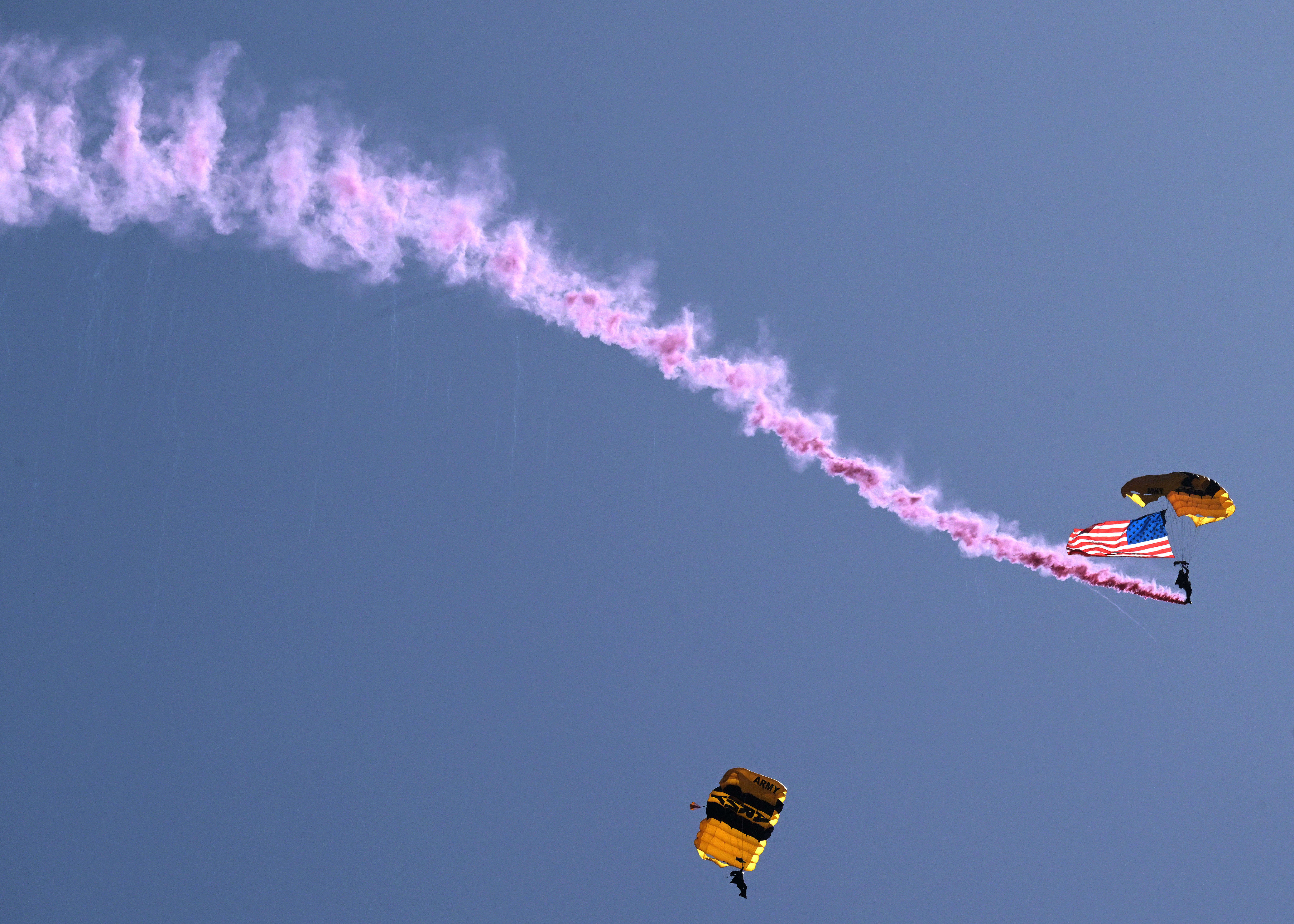 United States Army paratroopers desend with the American Flag during...