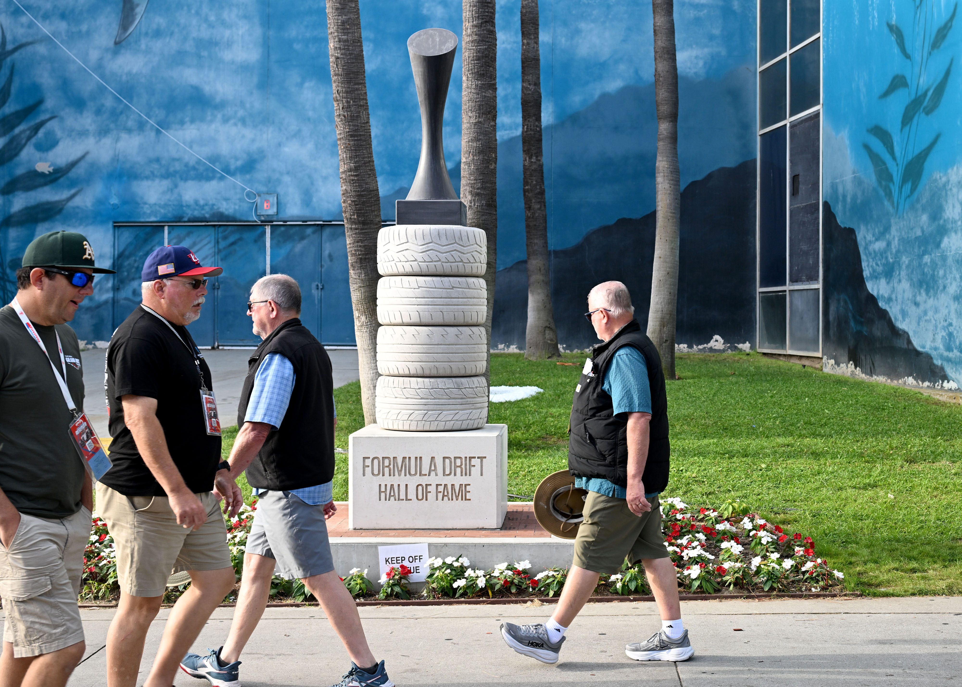 People walk by the Formula Drift Walk Of Fame statue...