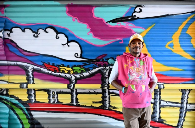 Artist, Lajon Miller, stands next to his mural of a rollercoaster at the Pike, photographed on Tuesday, April 7, 2026. The Acura Grand Prix of Long Beach partnered with Long Beach-based nonprofit Creative Class Collective to commission a series of special murals on three of the event's pedestrian bridges. (Photo by Dean Musgrove, Los Angeles Daily News/SCNG)