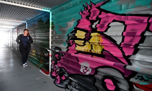 Something new this year includes murals ilike this one by artist, Jamiene "DLUX" Andreozzi walkimg next to her mural of a female racer in a pedestrian bridge on Tuesday, April 7, 2026. (Photo by Dean Musgrove, Los Angeles Daily News/SCNG)