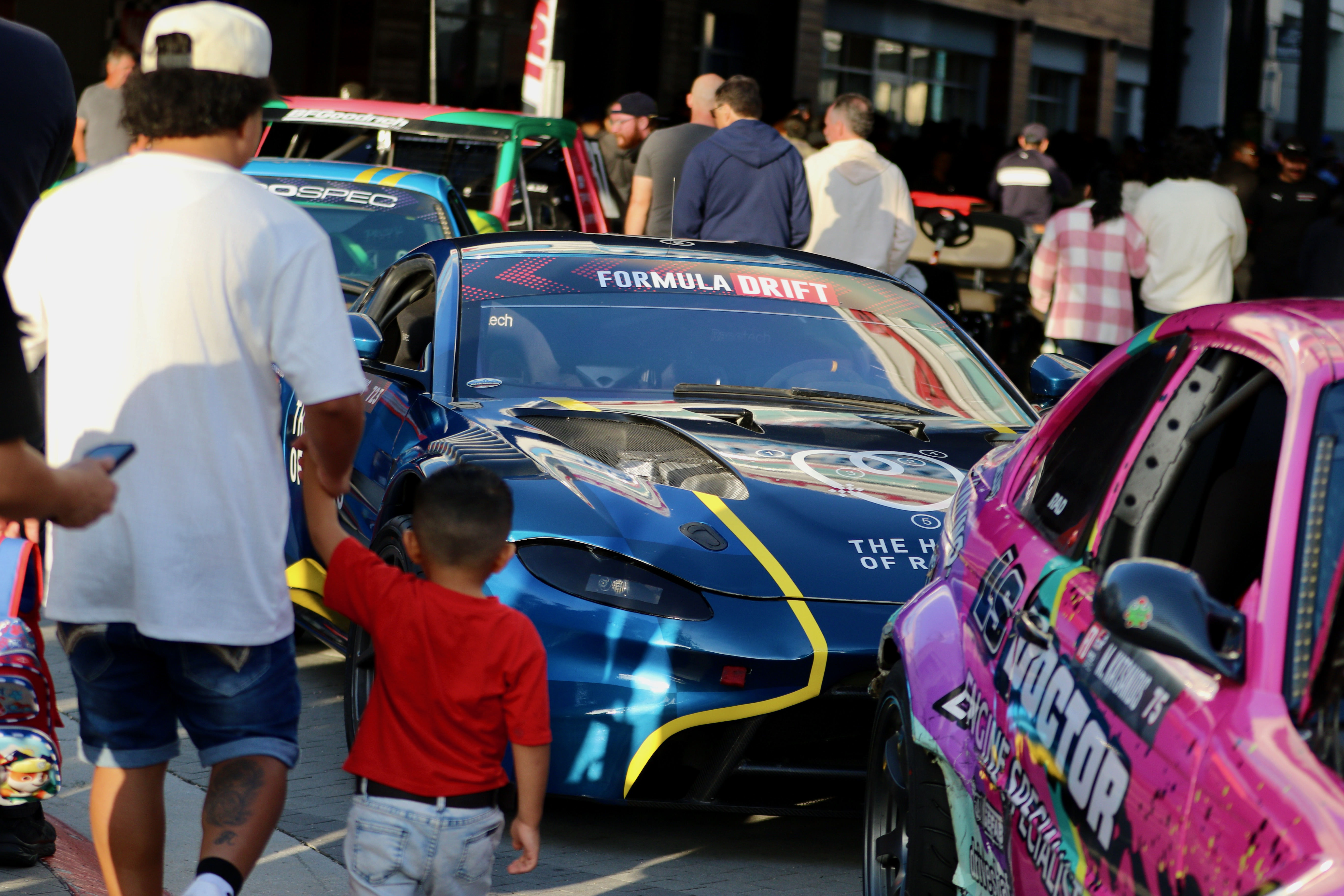 Attendees check out the various racing series cars and meet...