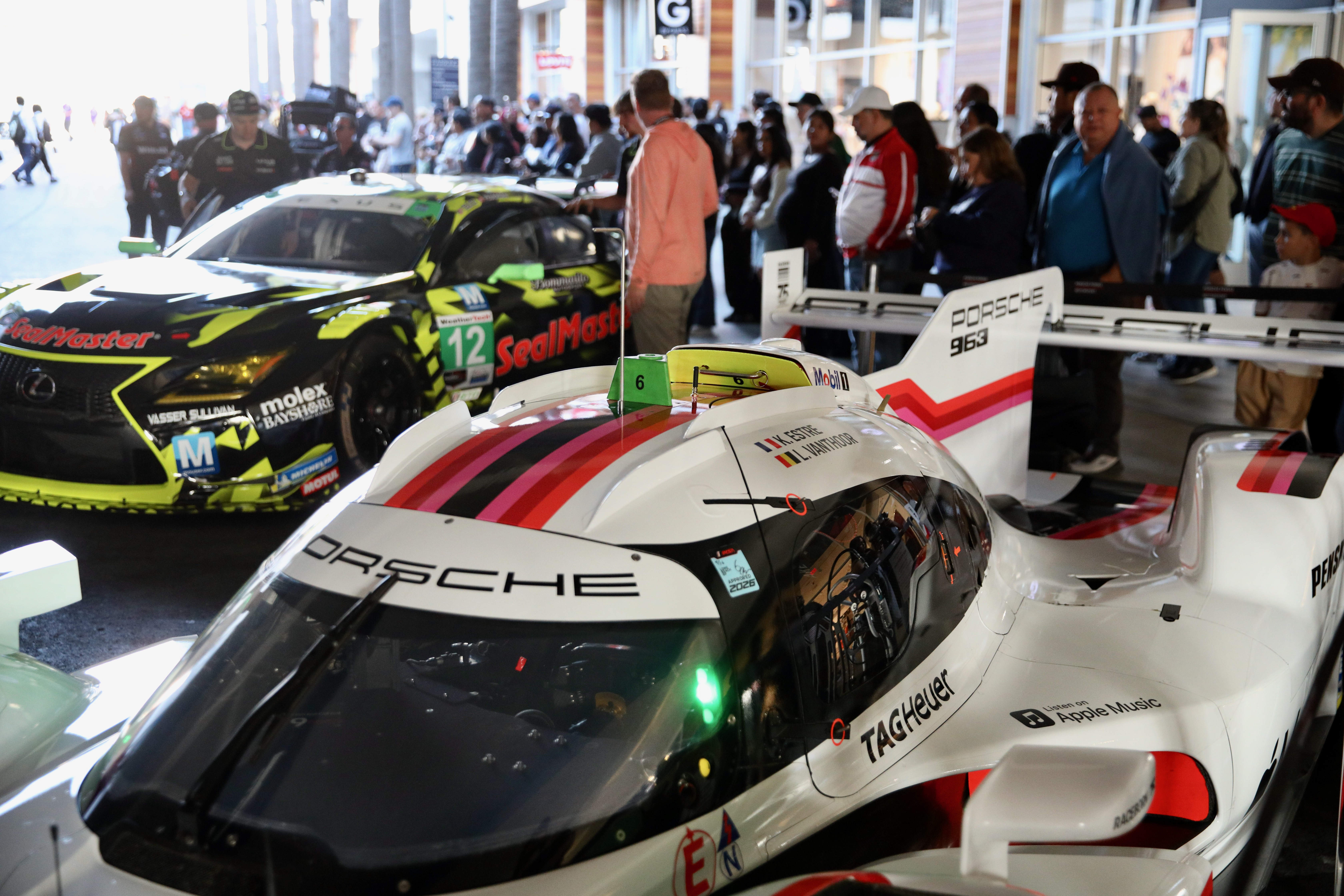 Attendees check out the various racing series cars and meet...
