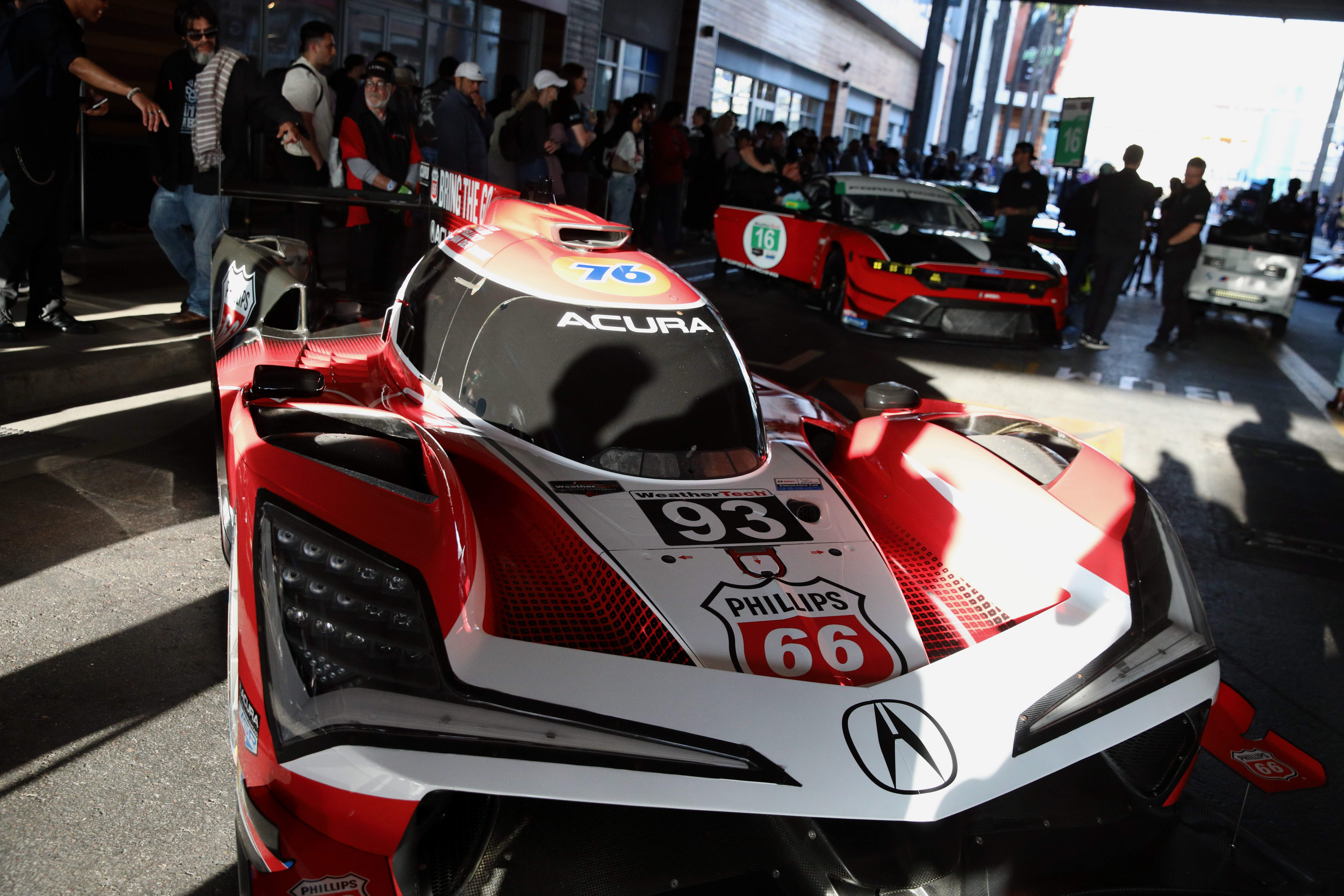 Attendees check out the various racing series cars and meet...