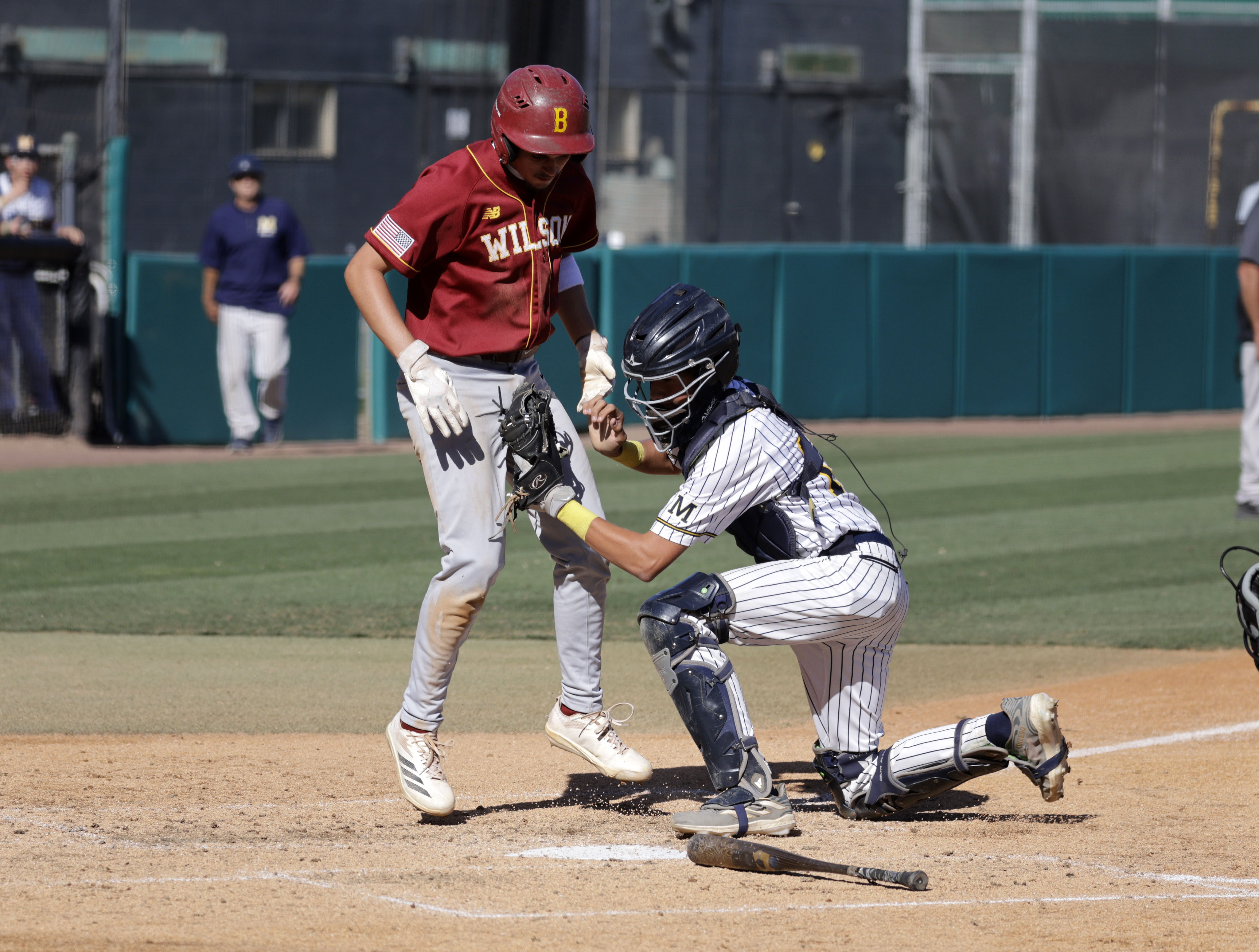 Wilson’s Cade Miller (2) is tagged out by Millikan catcher...