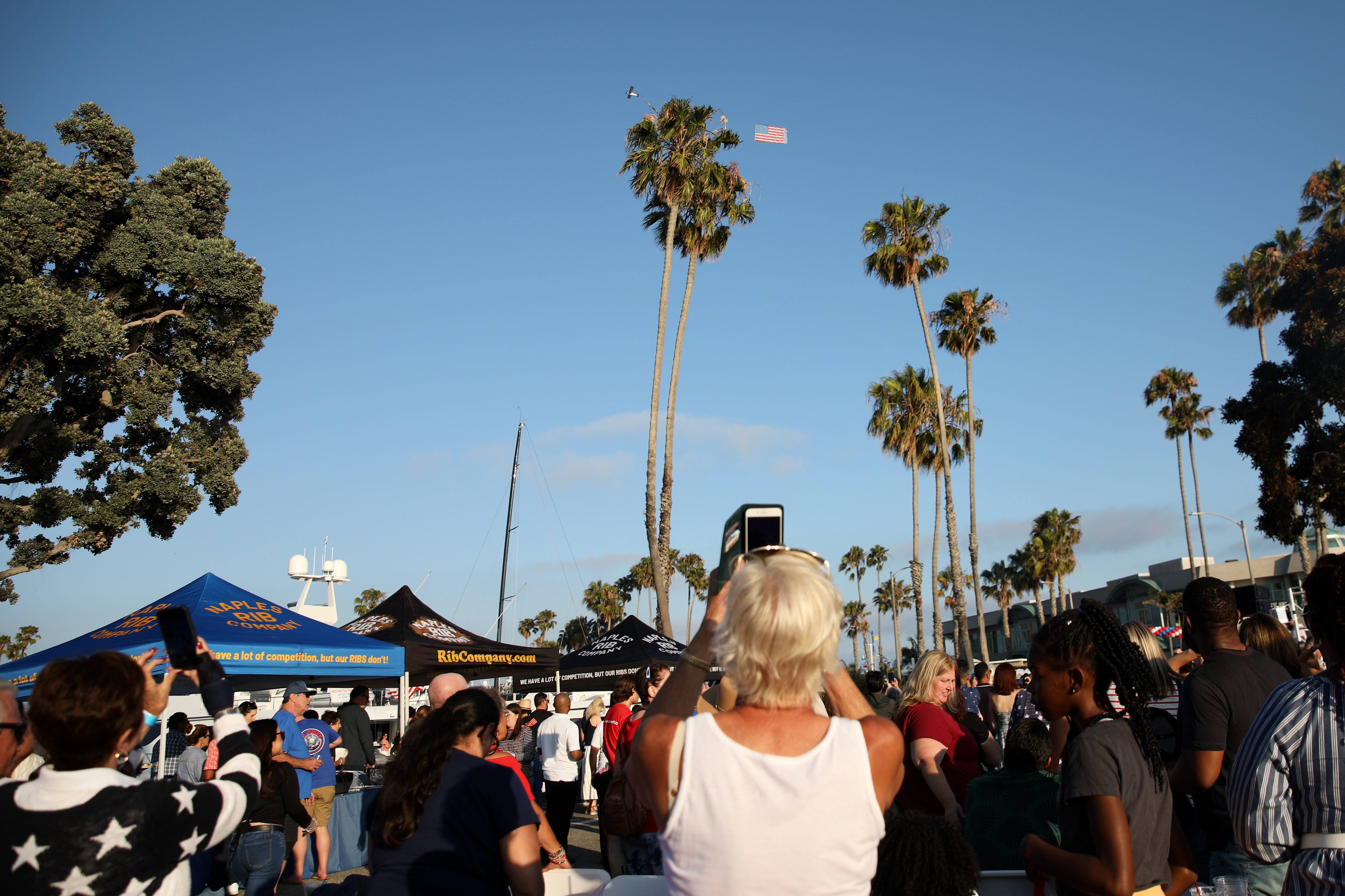 Attendees photograph an American flag being towed high in the...