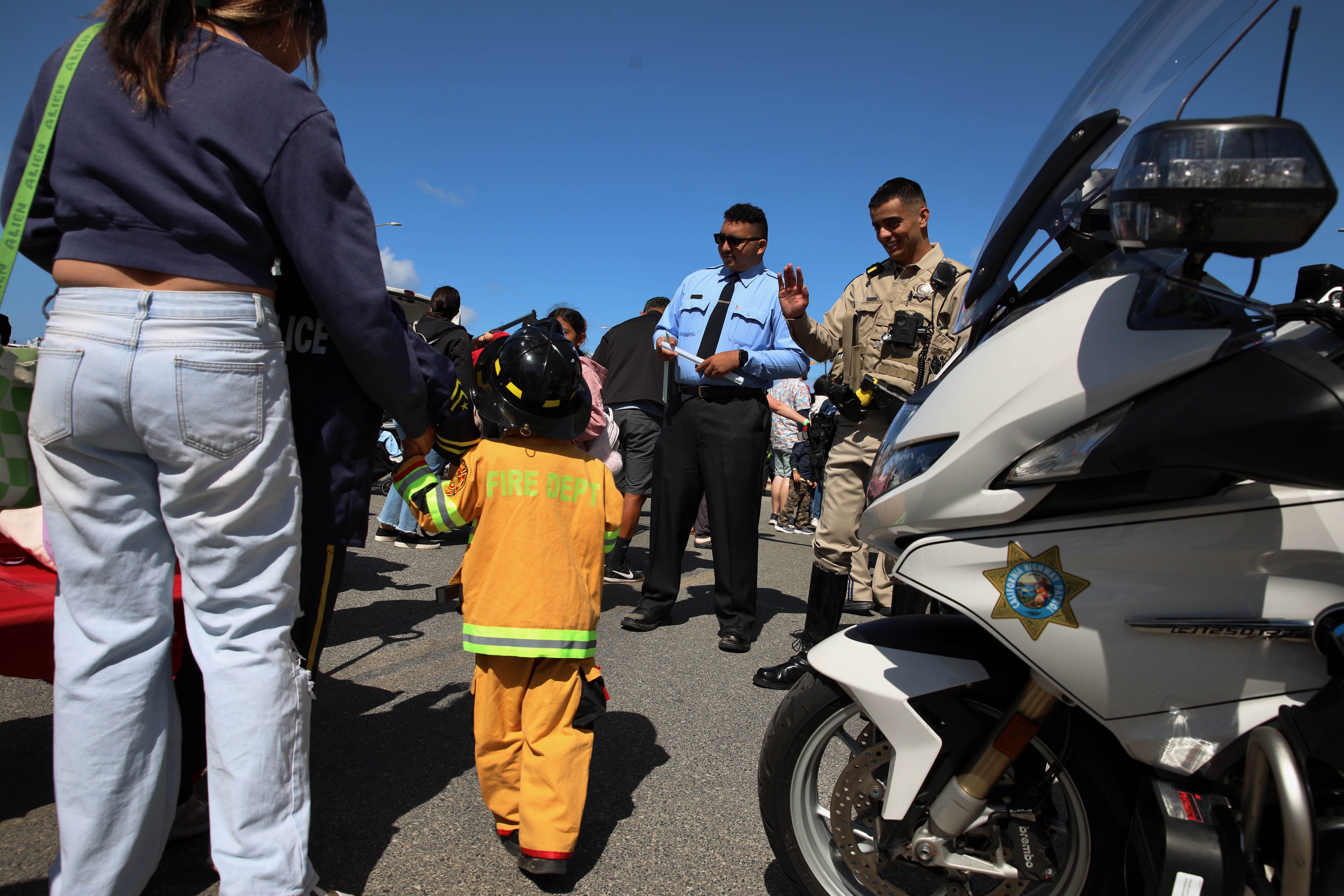 A CHP officer greets a youngster dressed as a fireman...