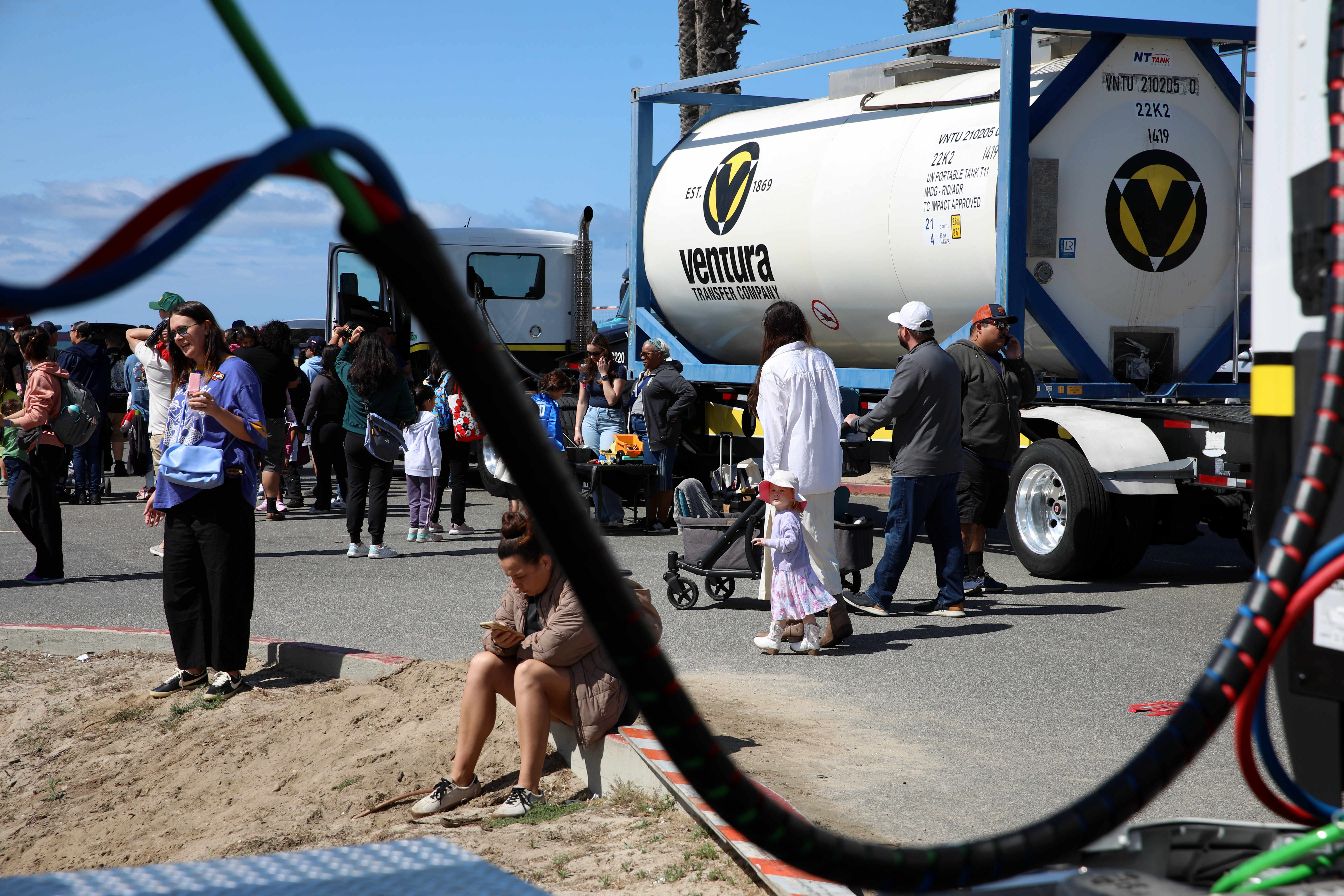 Visitors stroll past an array of trucks, safety and law...
