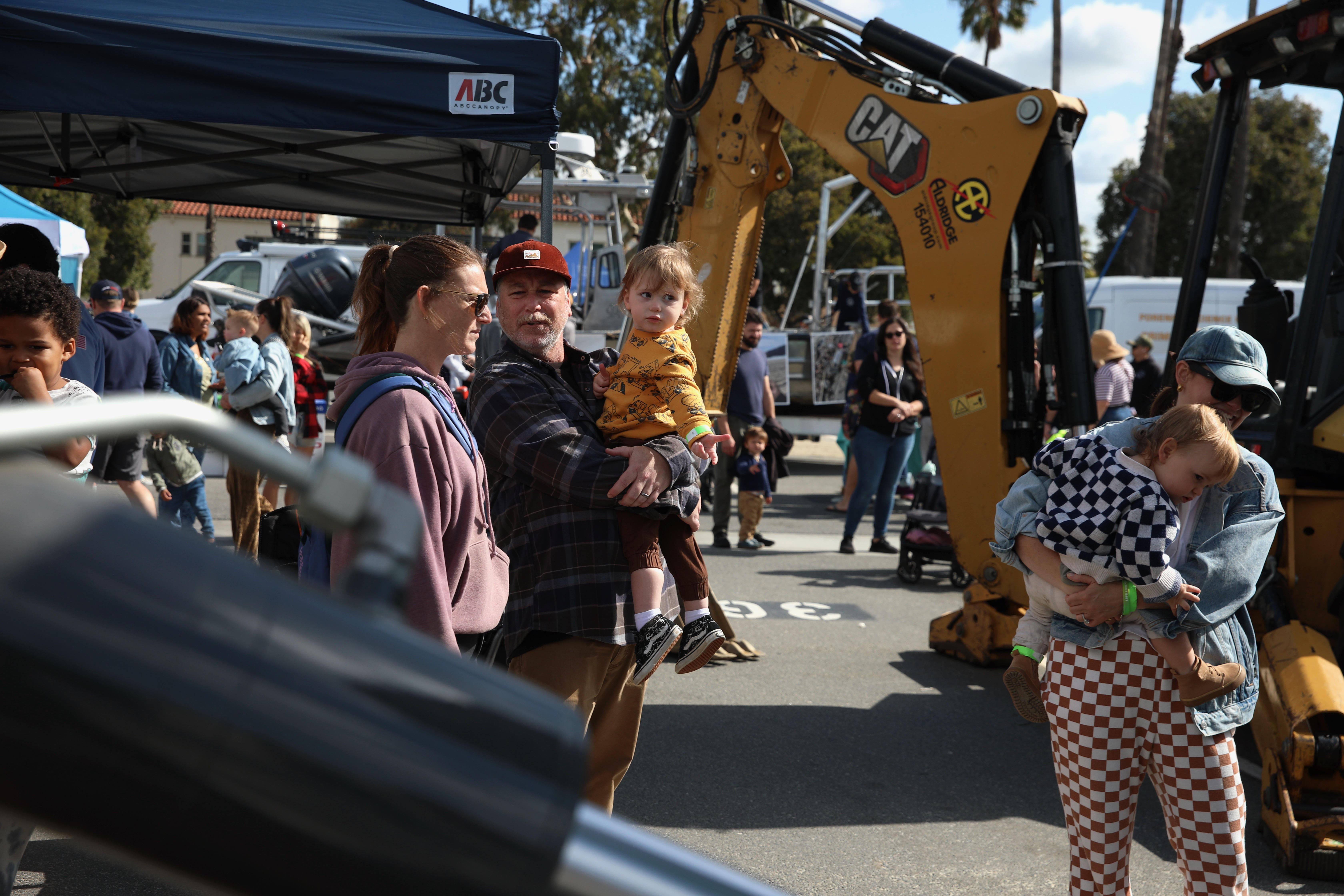 Visitors stroll past an array of trucks, safety and law...