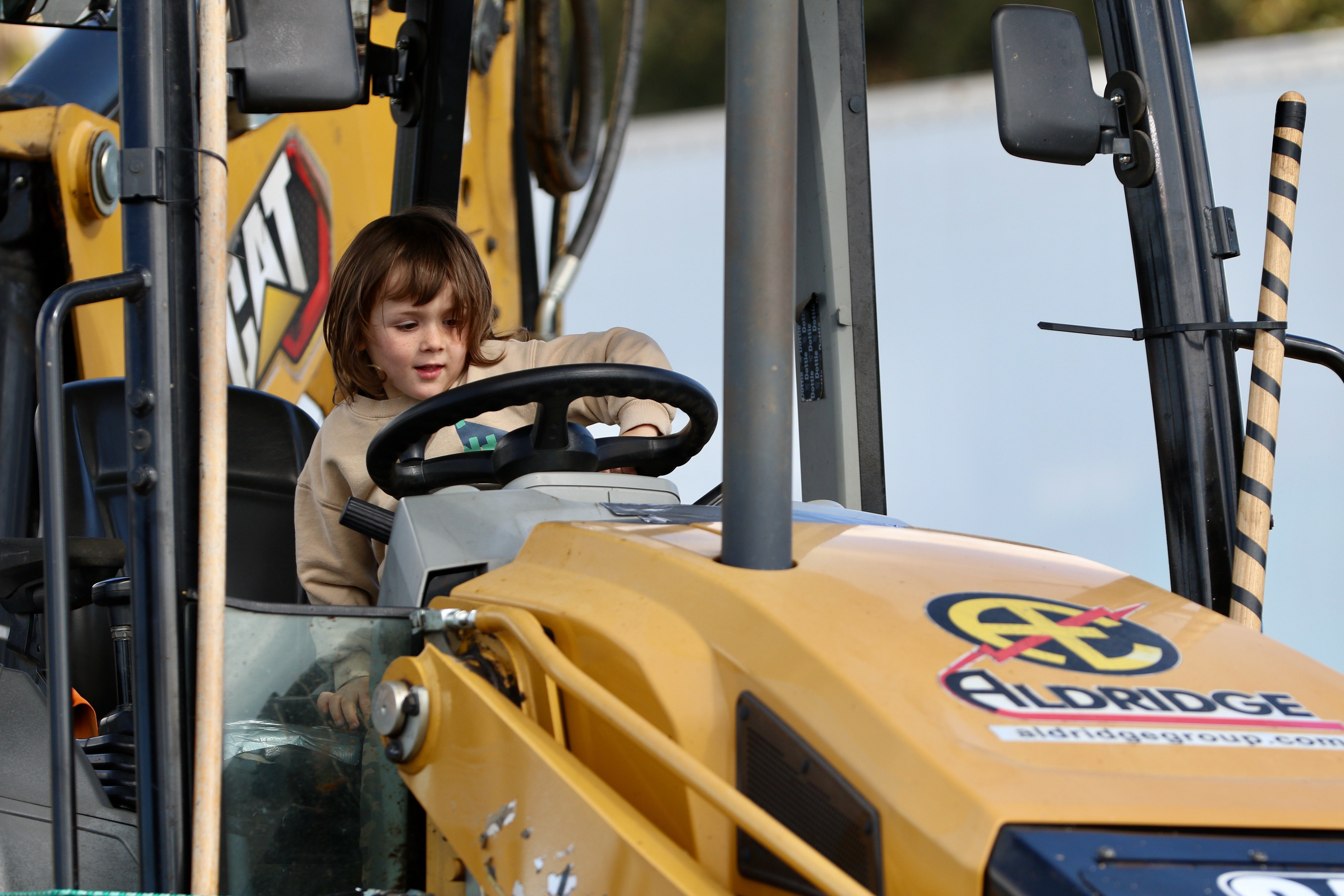 A youngster mans the wheel of an excavator at the...