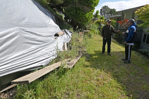 Donald Parker of the Marin City Community Services District, left, chats with resident Curtis Finley by a partially collapsed retaining wall behind residences on Drake Avenue on Tuesday, April 14, 2026. (Alan Dep/Marin Independent Journal)
