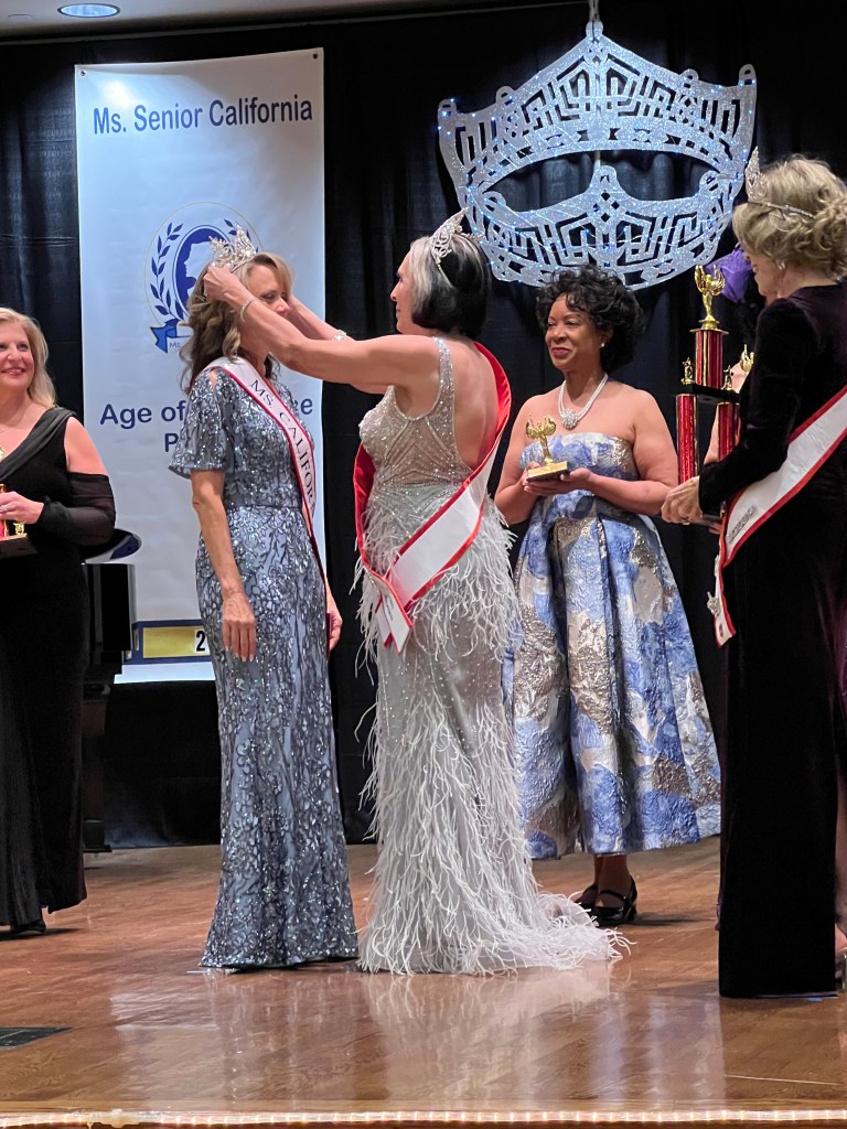 A crowning ceremony of Ms. Senior California with women in elegant gowns on stage.