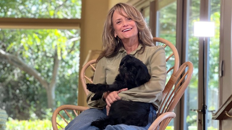 woman holding a small black dog