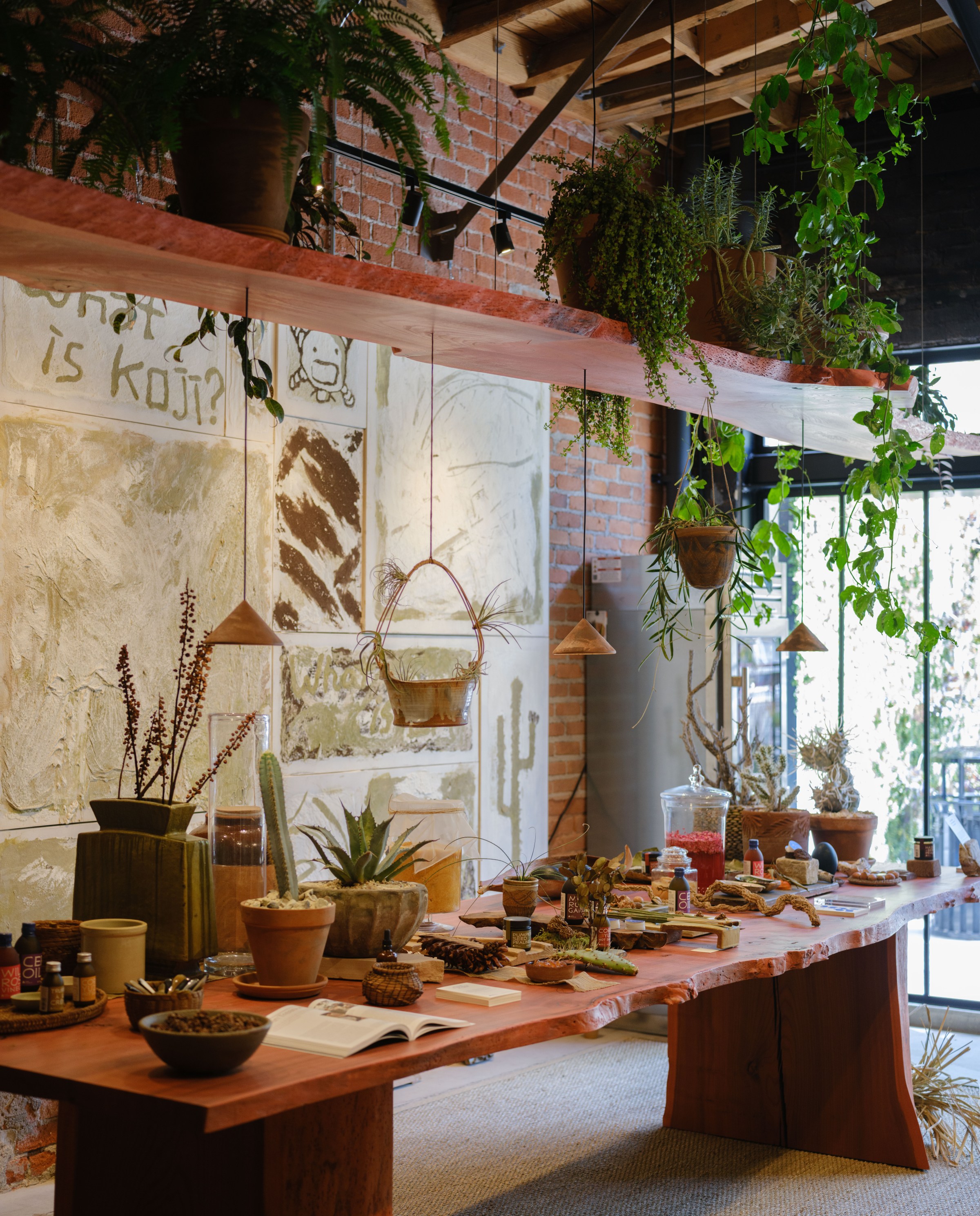 Long wood table inside Noma Projects covered in product.