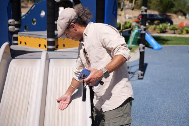 Jason Douglas, UC Irvine associate professor and vice chair of health, society and behavior, conducts fieldwork measuring the surface temperatures of park equipment. (Photo by William Pomeroy)