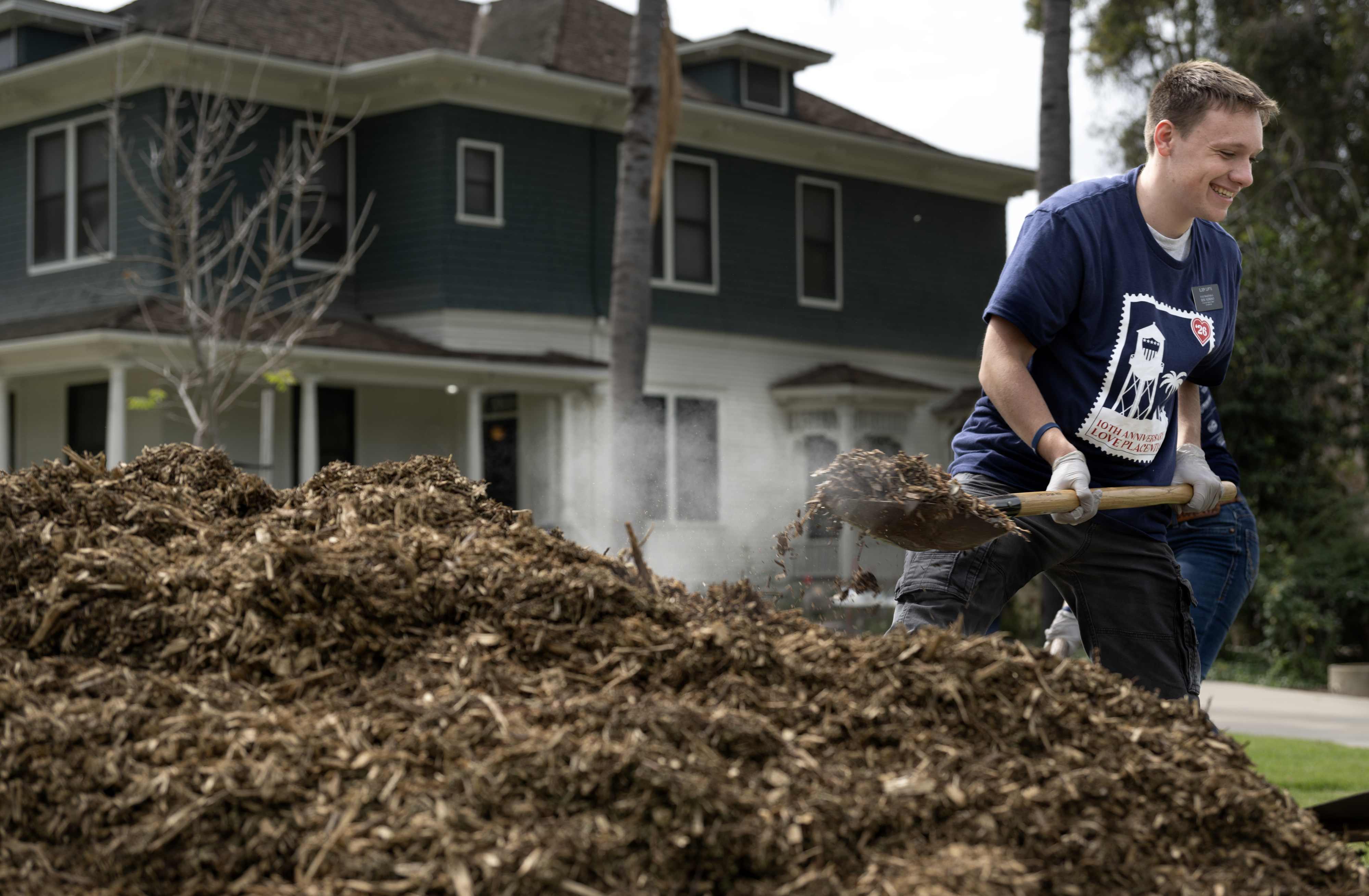 Love Placentia volunteer Tyler Glenn shovels mulch onto a tarp...