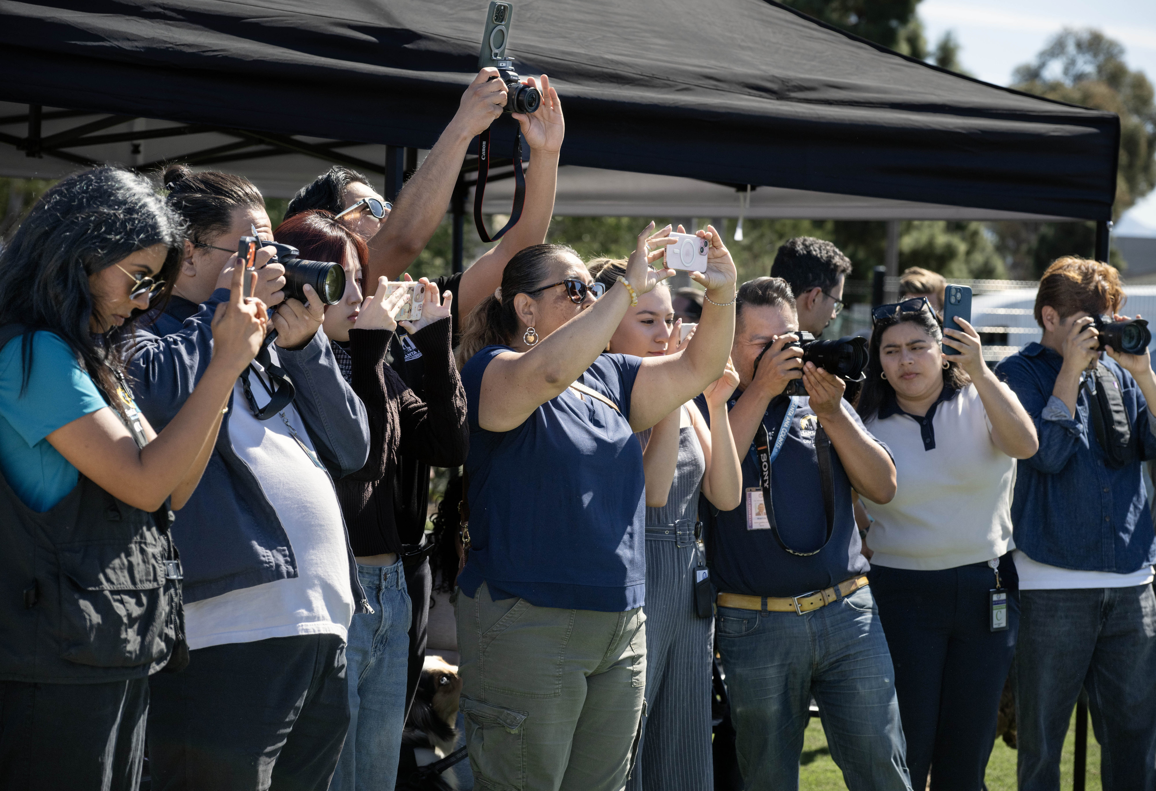 People are poised with their cameras during a ribbon-cutting ceremony...