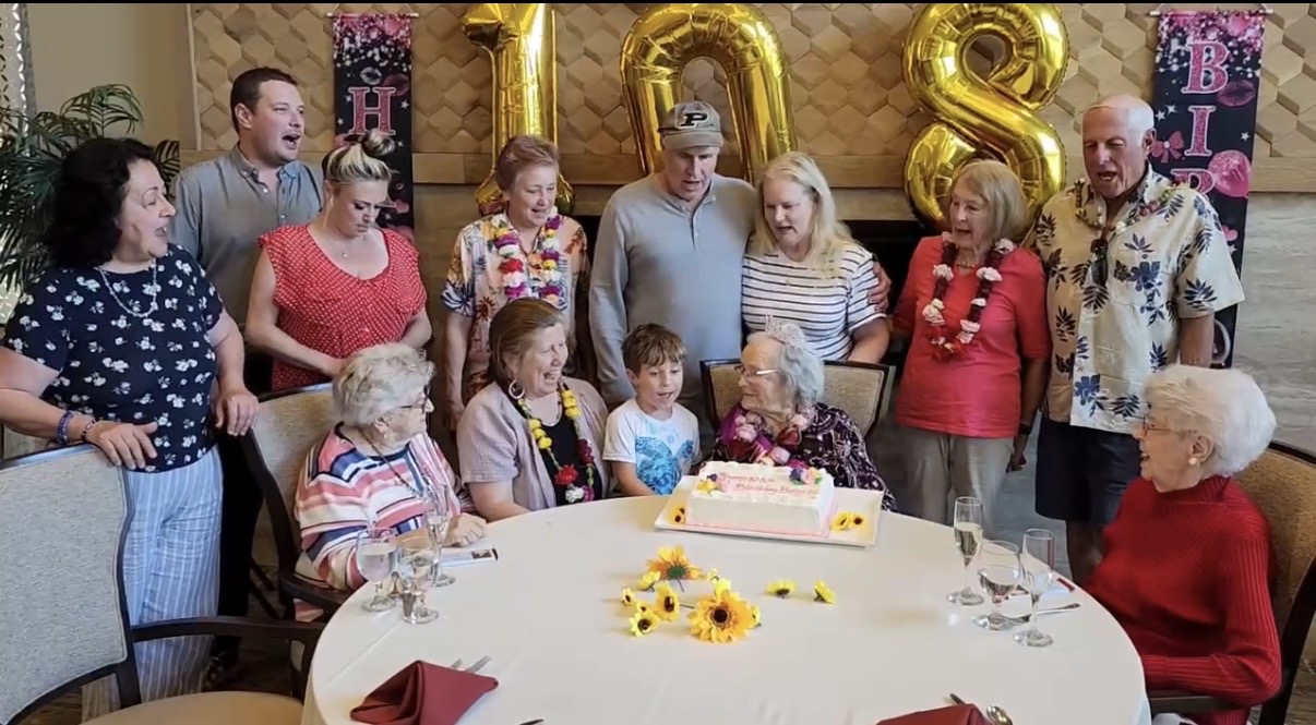 Betty Haver, seated with her cake, surrounded by family and...