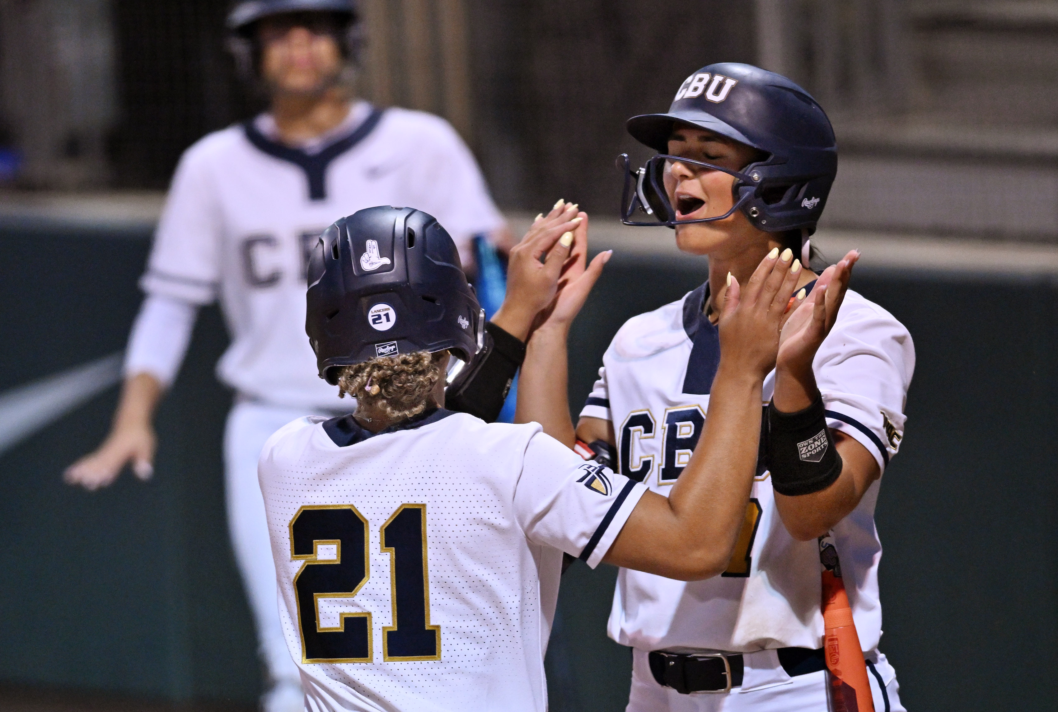 California Baptist University’s Jasmine Goins (#21) celebrates with Bella Wellbaum...