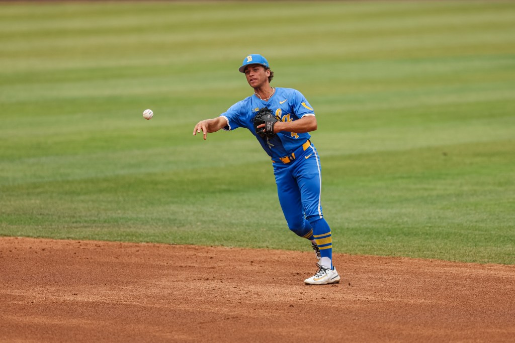A baseball player in a blue and yellow uniform throwing a baseball.