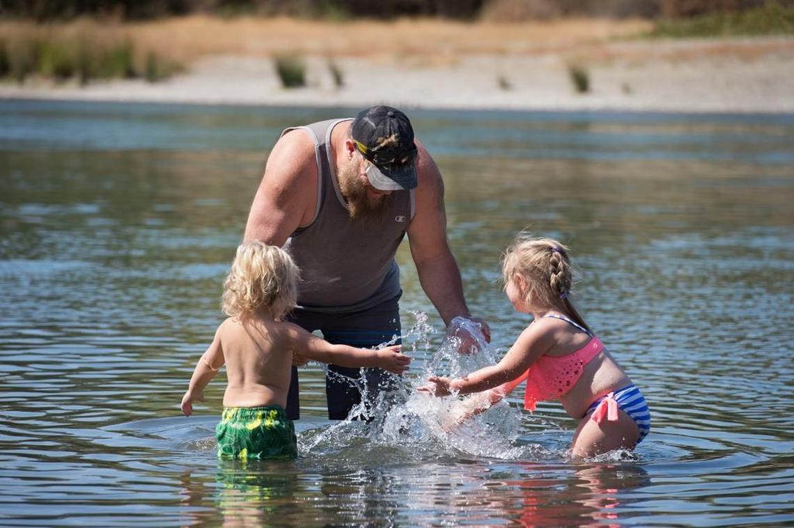 Matthew Johnson of Rancho Cordova, center, plays with his children, Logan Johnson, 2, left, and Fiona Johnson, 3, in the American River.