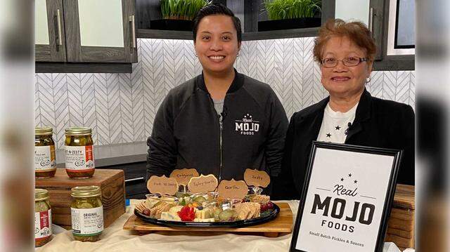 Dee Siazon and her mother Delia "Mama Mojo" Siazon showcase Real Mojo Foods pickles alongside crackers, cheese and fruit as part of a platter. The Hot-n-Zesty Semi-Sweet & Spicy pickle chips are a finalist in the 2026 Good Food Awards.