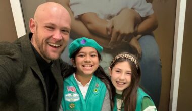 man posing with two girl scouts