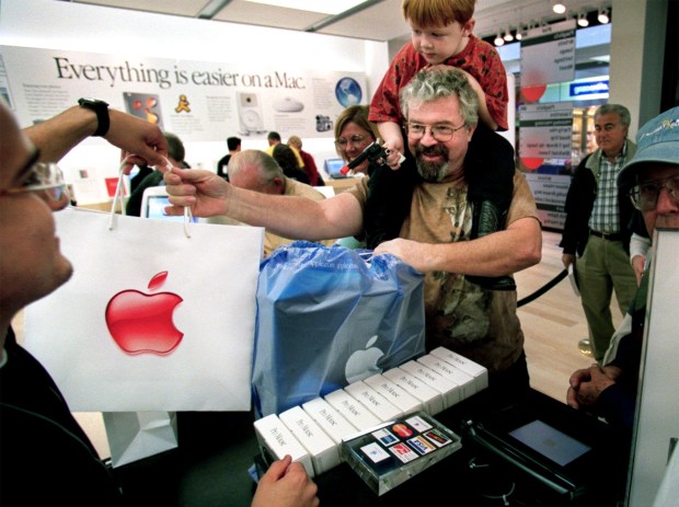 Ross McIntosh, along with his son, Ryan,6, picks up his new Apple Titanium Powerbook during the opening day of the Apple Store in South Coast Plaza. The opening drew over a thousand people, and featured teeshirt give aways, a Genius Bar where computer users could get answers to their Mac questions as well as demos in the apple theater. (Bruce C. Strong/Orange County Register,