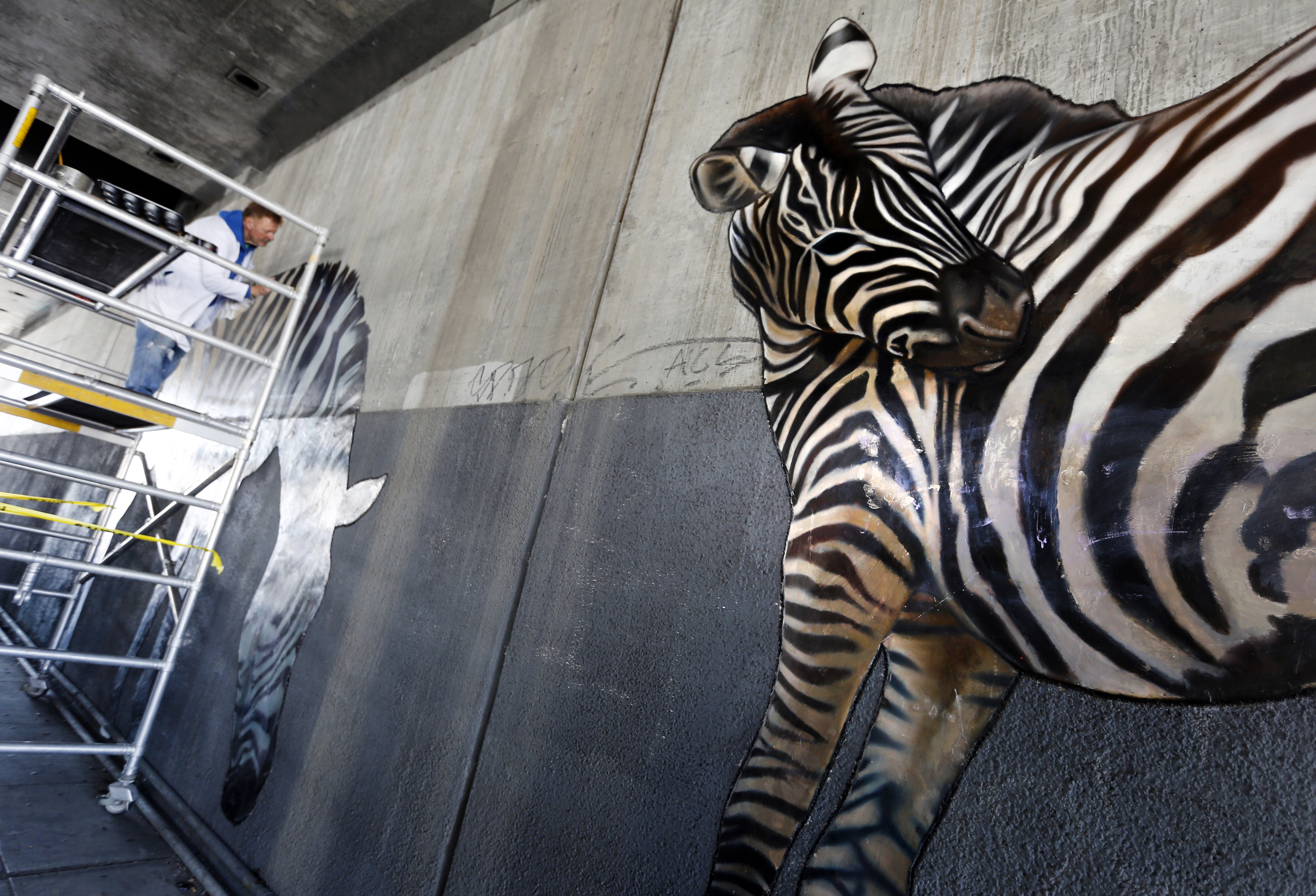 Dan Fontes paints on a scaffolding under Interstate 580 on...