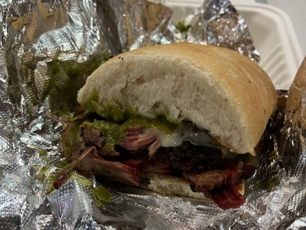 The Gaucho sandwich at Redwood City Barbecue is filled with brisket, chimichurri, grilled onions and melted provolone cheese, and is served with a side. (Kate Bradshaw/Bay Area News Group)