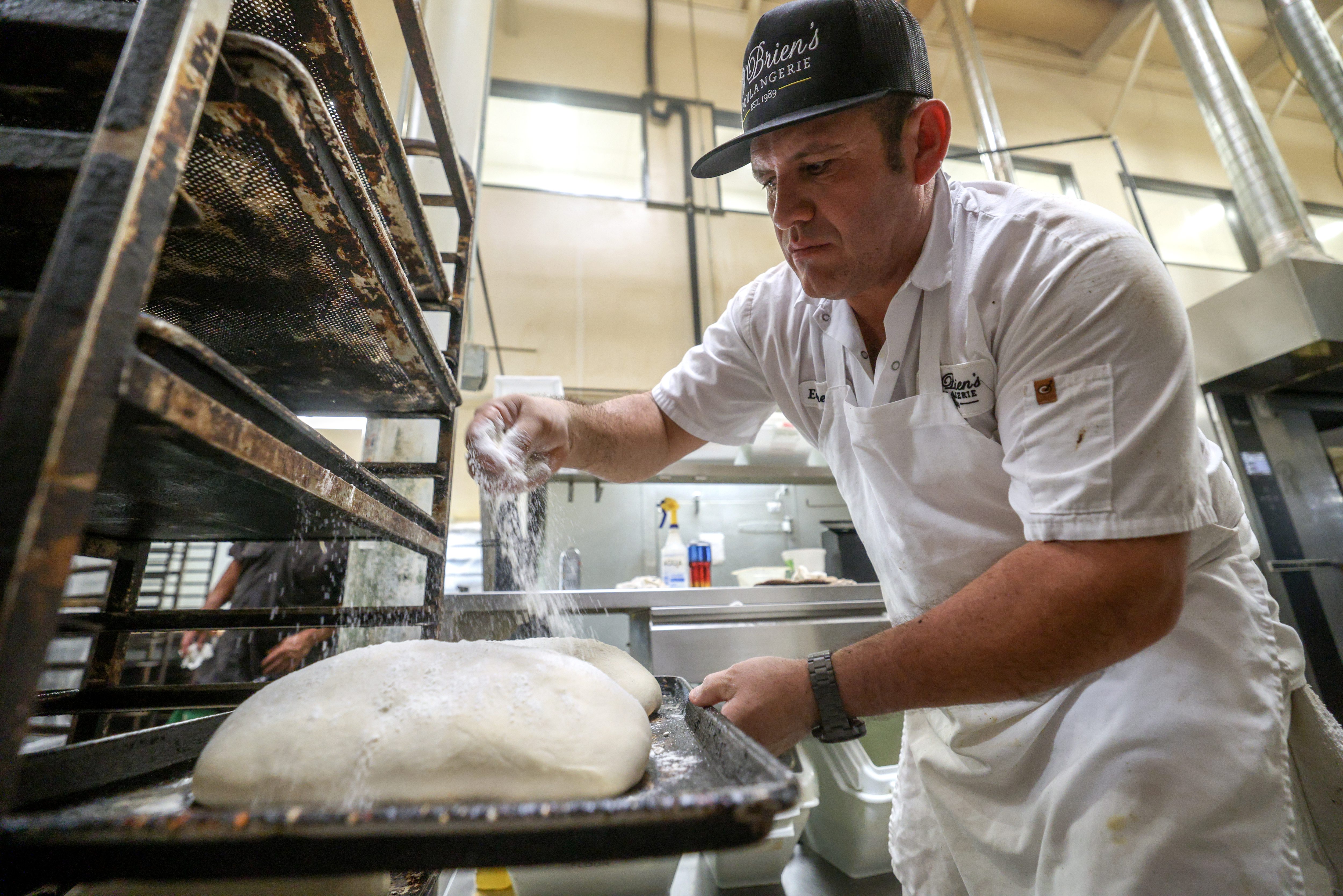 Baker Ernesto Soto sprinkles flour over loaves of sourdough bread...