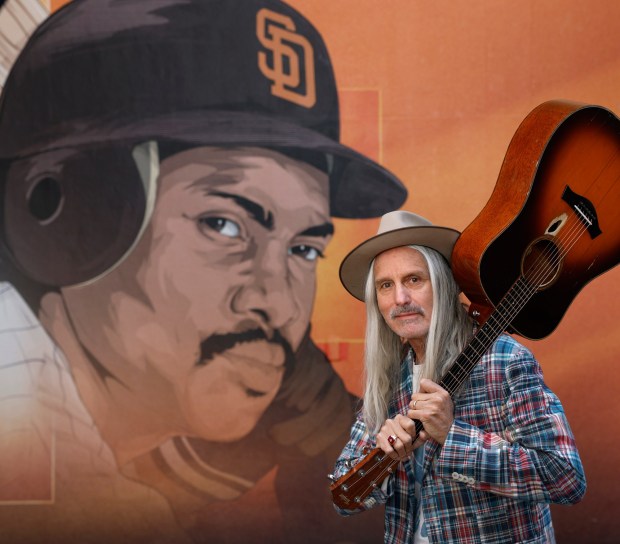 Singer-songwriter Steve Poltz poses for a portrait next to a mural of Padres legend Tony at Petco Park on April 13, 2026 in San Diego, CA. (K.C. Alfred / The San Diego Union-Tribune)
