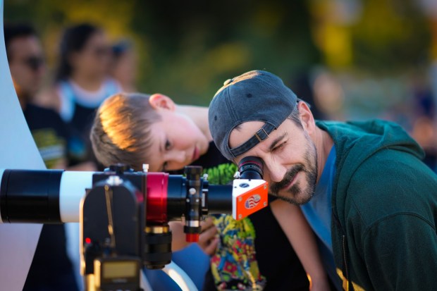 Keith Morrison and his 5-year-old son, Slade, from Oceanside, observe the sun through a 60 mm telescope provided by astronomer Craig Storms during the Dark Sky Festival held at Menghini Winery in Julian on Saturday, Aug. 16, 2025.   (Nelvin C. Cepeda / The San Diego Union-Tribune)